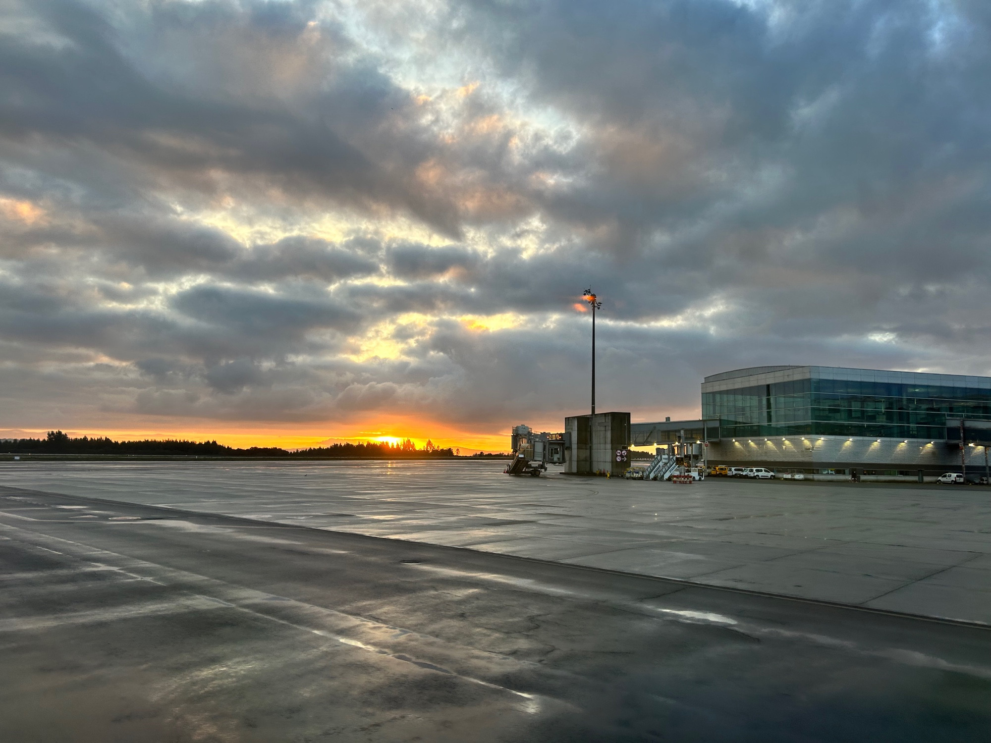 Foto de pista de aeropuerto al amanecer a pesar de estar nublado se ve el sol