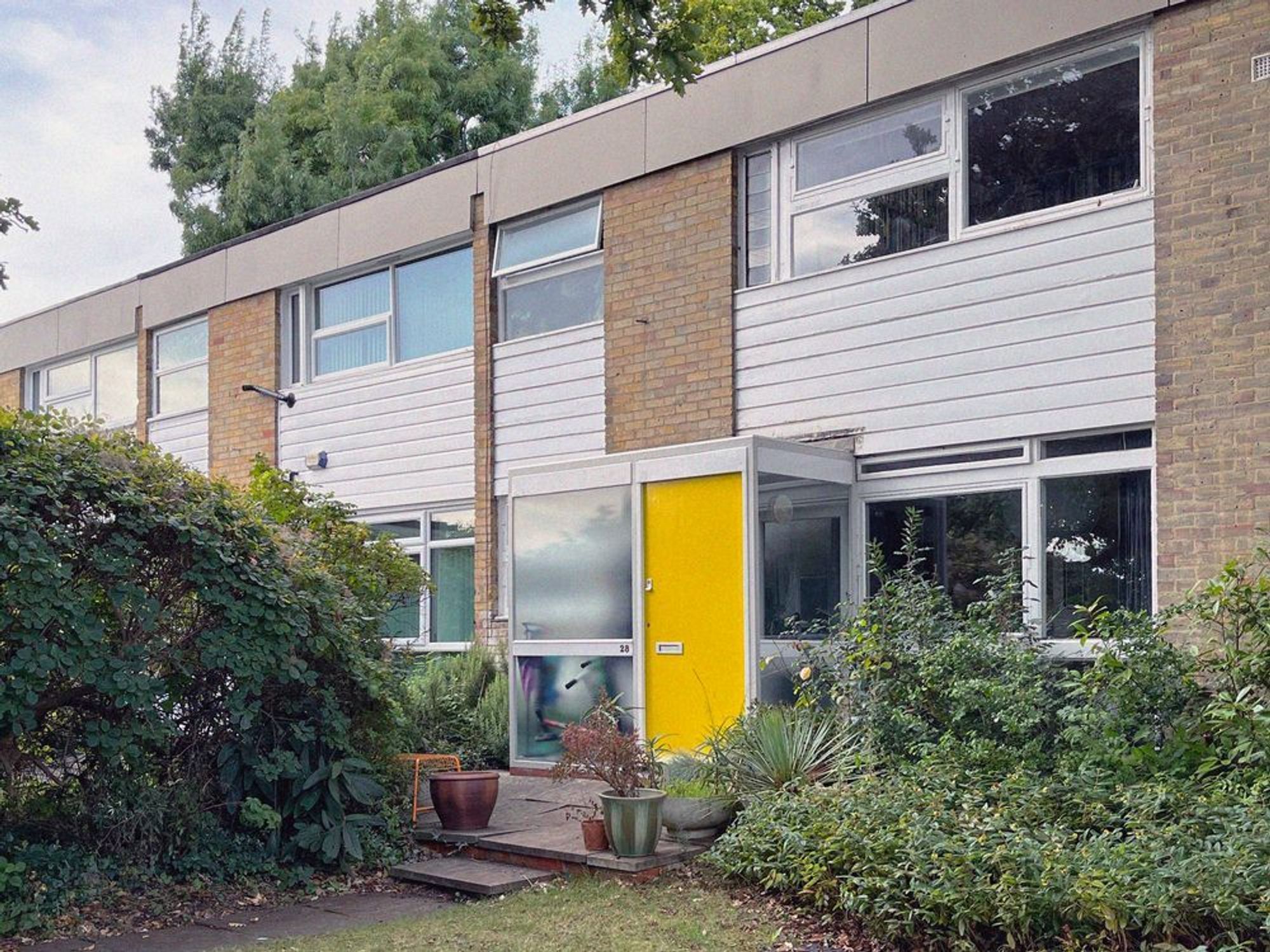 A colour photograph of a terrce of houses at West Oak in Beckenham, one with a yellow front door