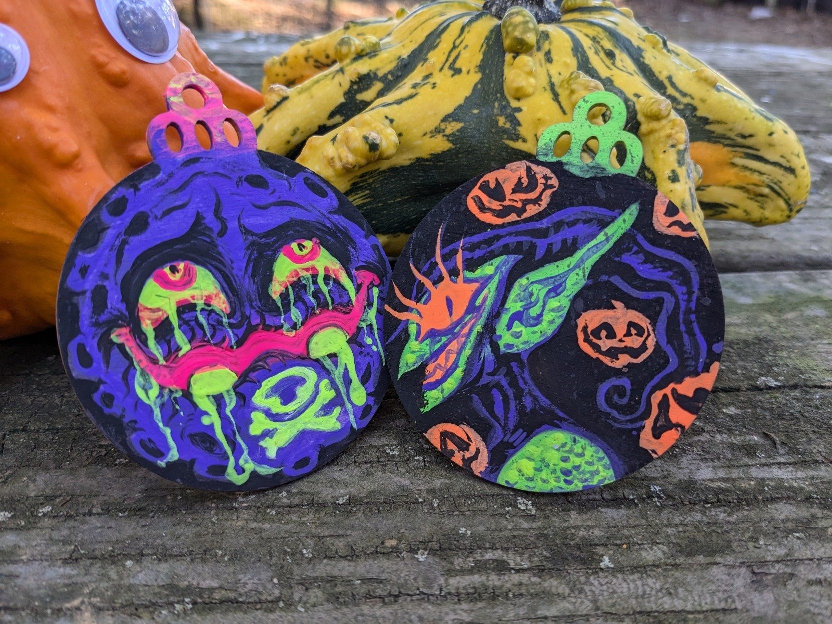 Koffing and green goblin paintings on circular pieces of wood.  Behind them are star shaped squash