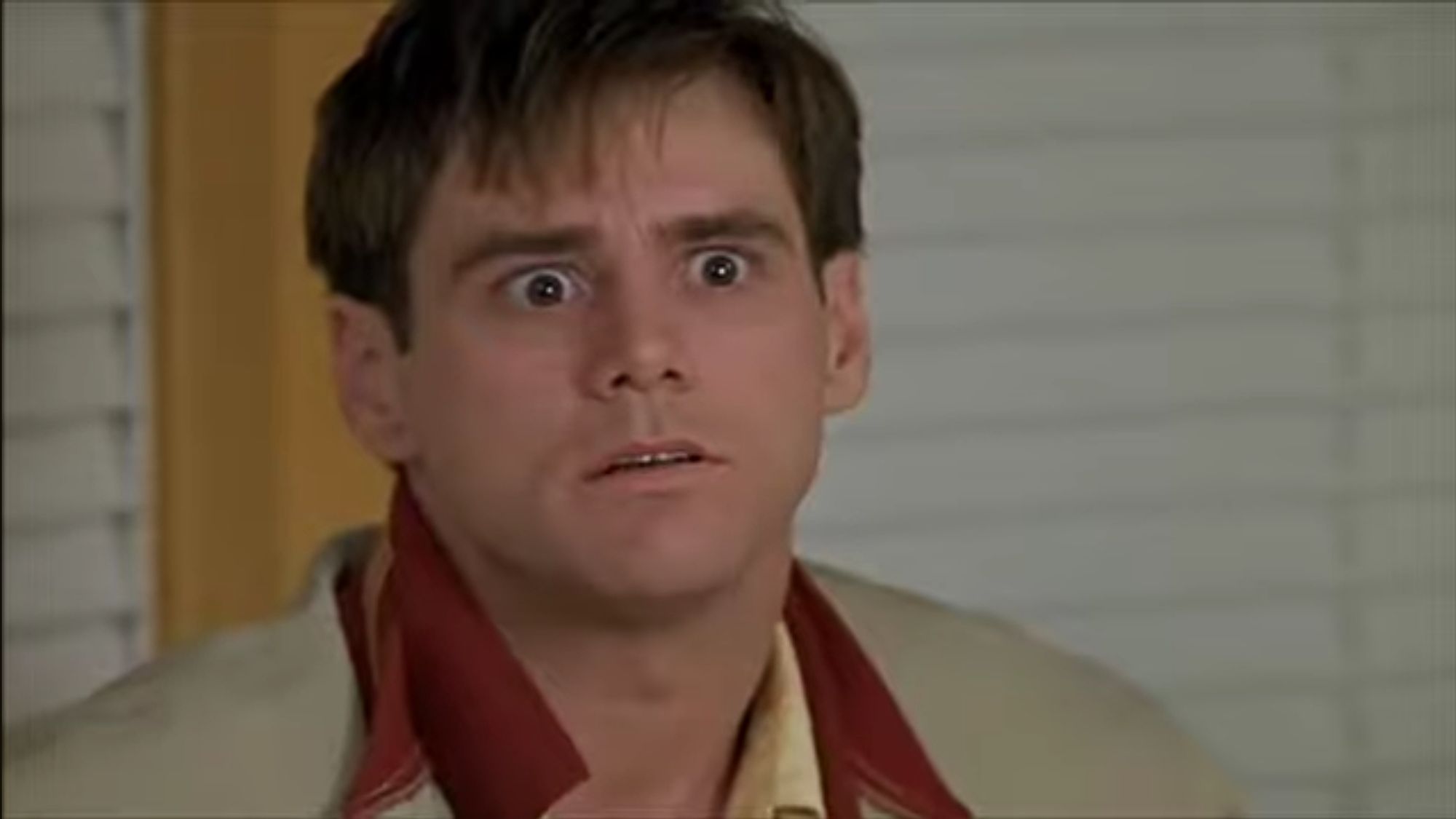 Jim Carrey from the movie The Truman Show looking wide eyed and confused. The image is from the scene where Truman's wife is doing an ad read for a chocolate drink and Truman is yelling "what the he'll are you talking about???"