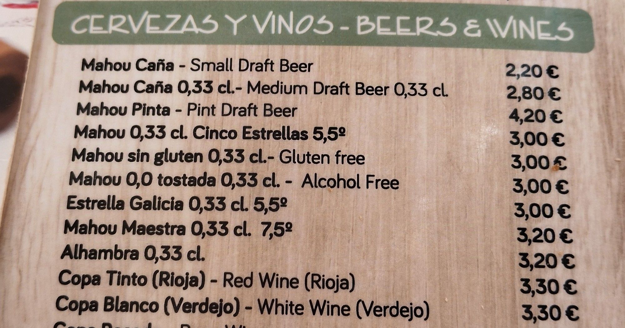 Part of a cafe menu, showing beer and wine prices. One of the beers is described as "Mahou sin gluten 0,33cl. - Gluten free"