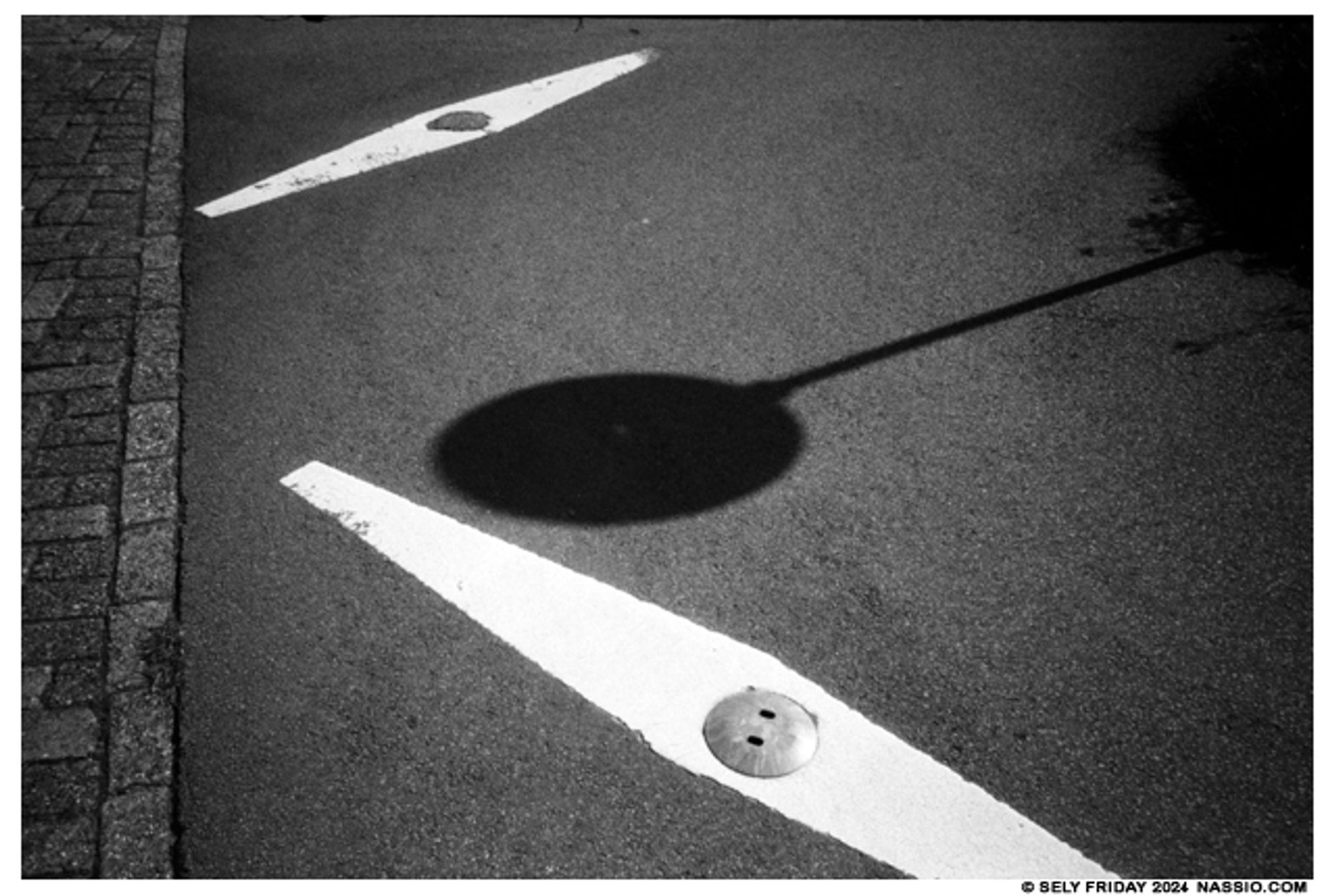 Street sign shadow on the pavement between two white lines