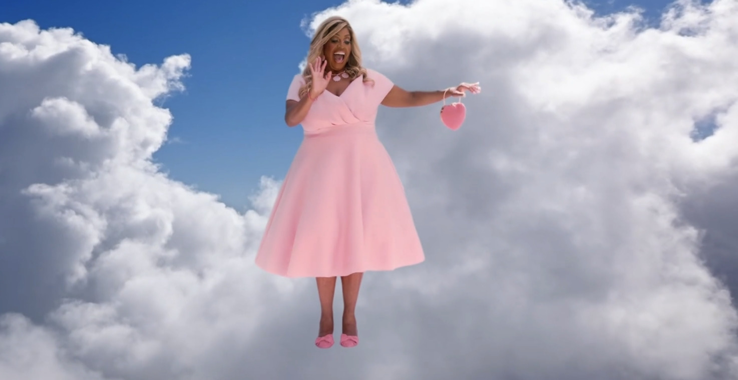 Alison Hammond wearing a Barbie-pink dress, pink shoes and a small, heart-shaped bag, floating in the sky and waving.