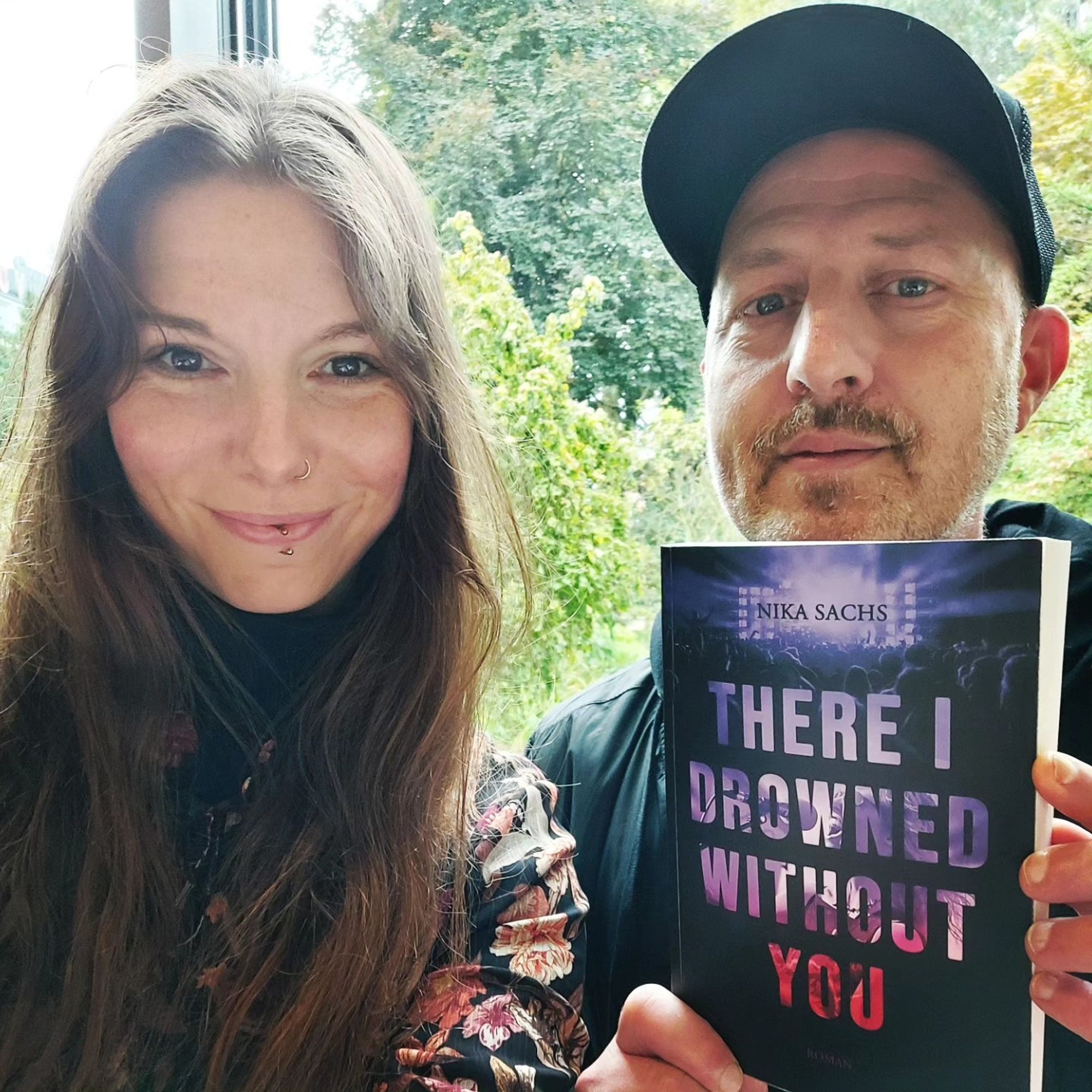 Autorin Nika Sachs (Karena Beissert) und Bassist Jan Hoffmann von Long Distance Calling halten das Crowdfundingbuch "THERE I DROWNED WITHOUT YOU" hoch.