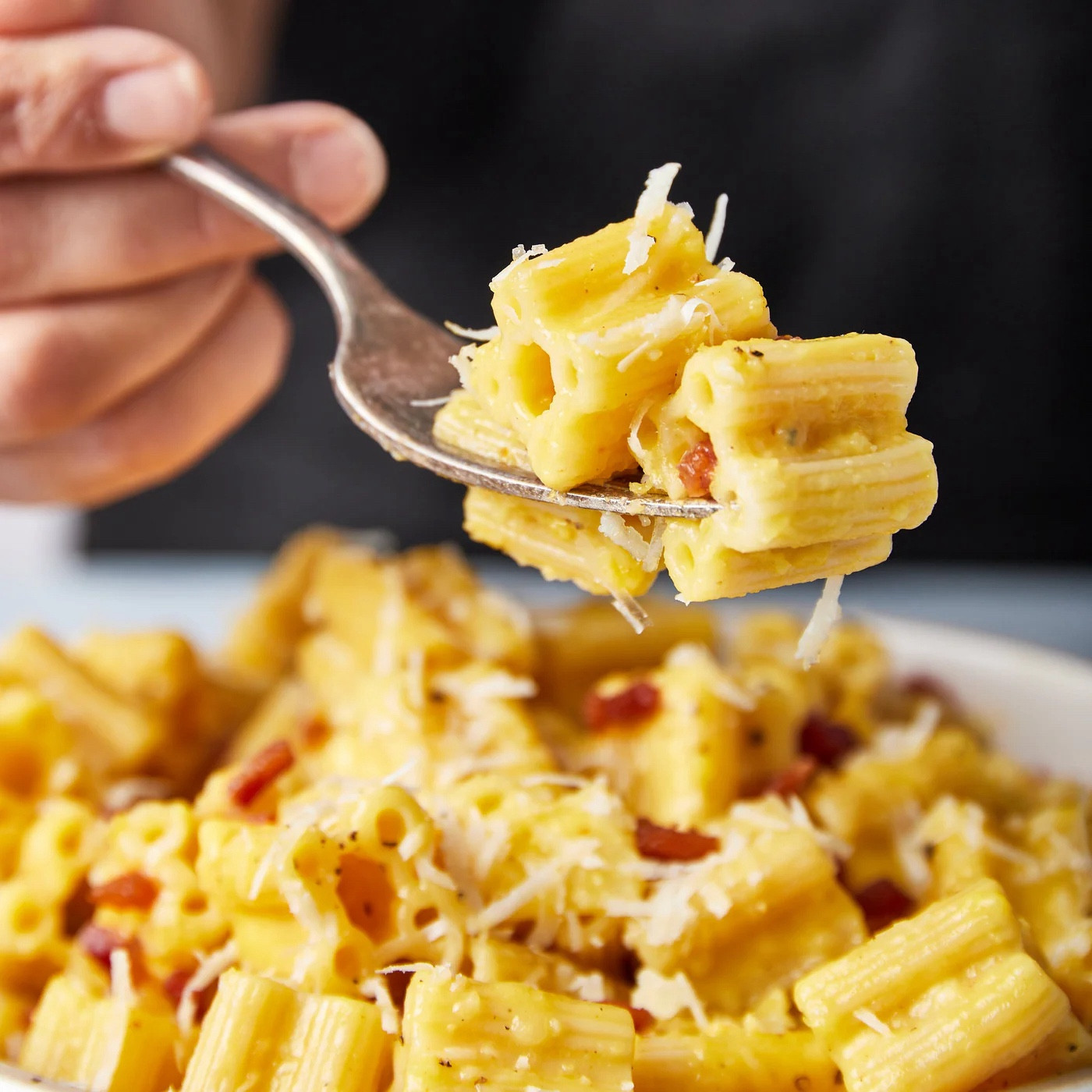 Quattrotini in a dish all sauced and cheesed up, with a fork holding several pieces. Tantalizing