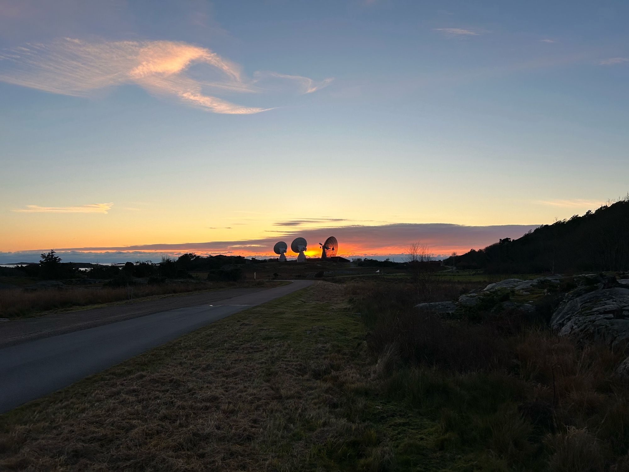 Three telescopes at a distance in silhouette against the sunset.