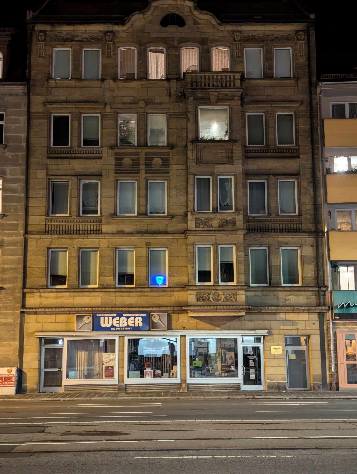 Nachts gegenüber der Haltestelle Maximilianstraße Nürnberg. Altbau mit Reklame im EG