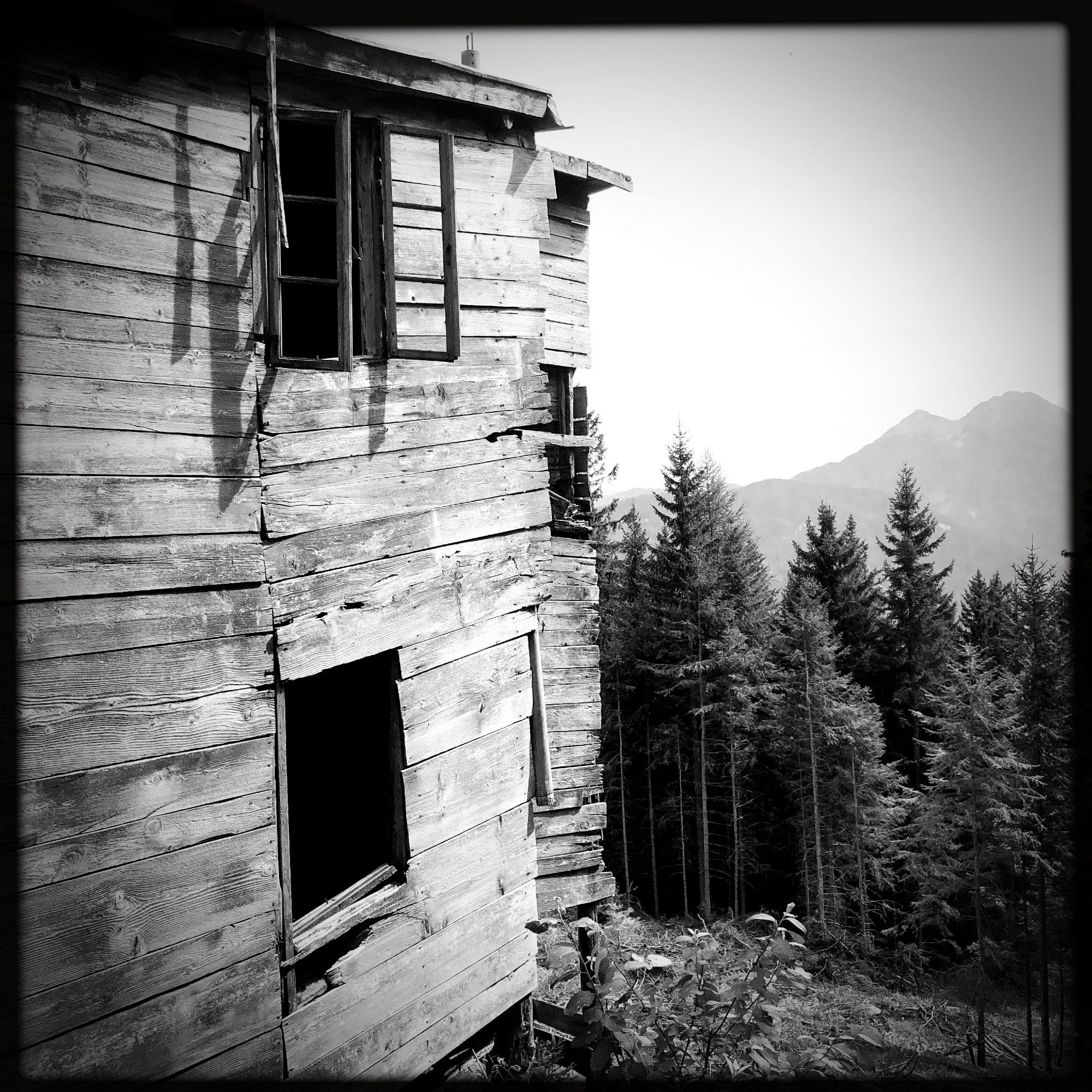 Una casa abbandonata vicino al sentiero e le cime delle montagne in lontananza