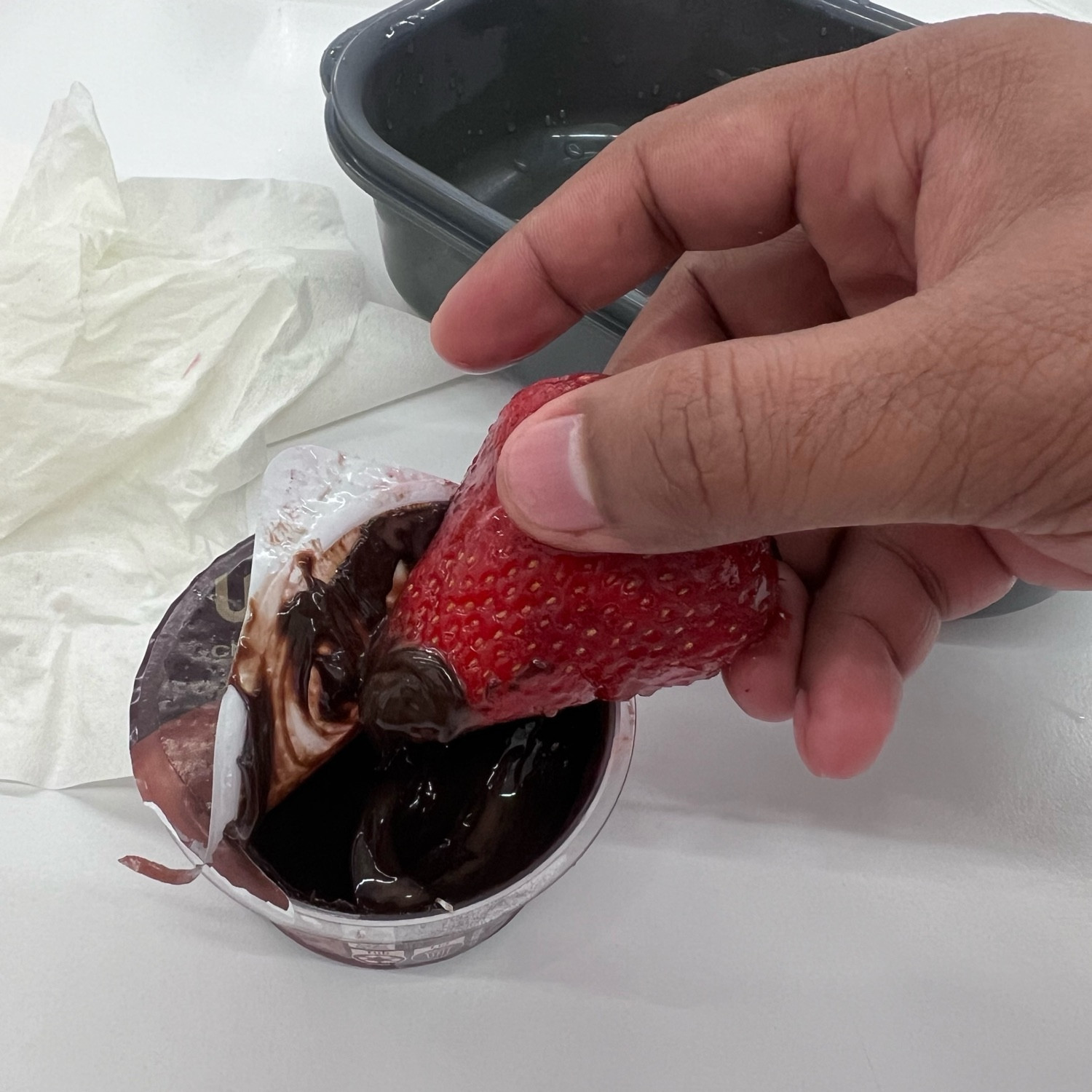 Strawberry being dipped into a chocolate dip