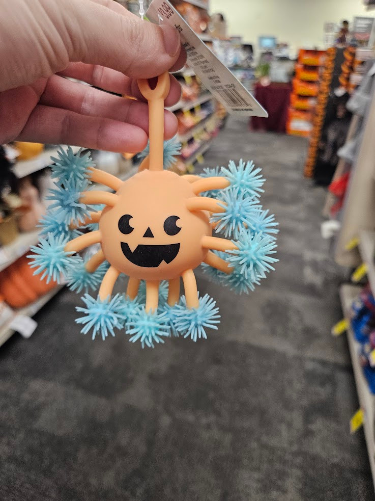 A squishy toy consisting of an orange ball with a jack-o-lantern face and maybe 20 tendrils coming out of it at all angles. At the end of each tendril is a blue Koosh-like spiky sphere.