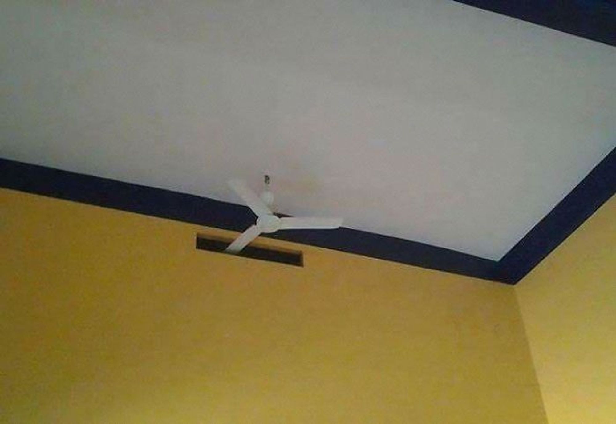 A ceiling fan mounted too close to the wall, so there is a gap cut in the wall to give it room to spin