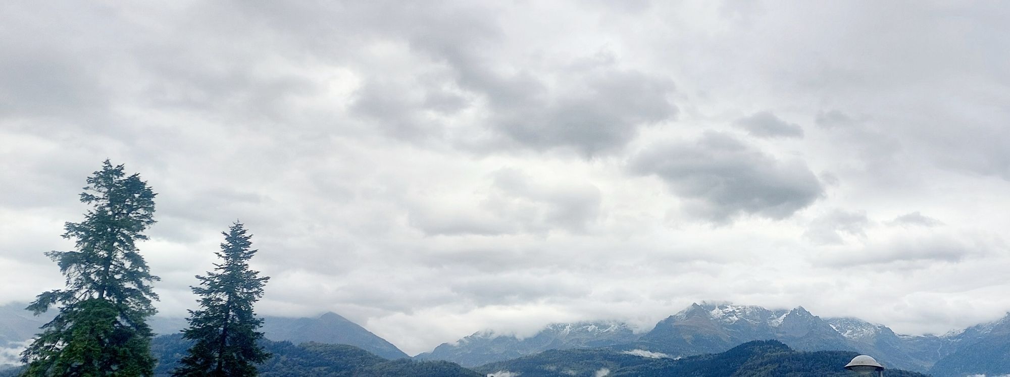 Sous un ciel gris, montagnes au loin avec un peu de neige sur les sommets.