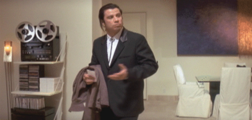 Vincent Vega looking to the camera confused with arm raised.