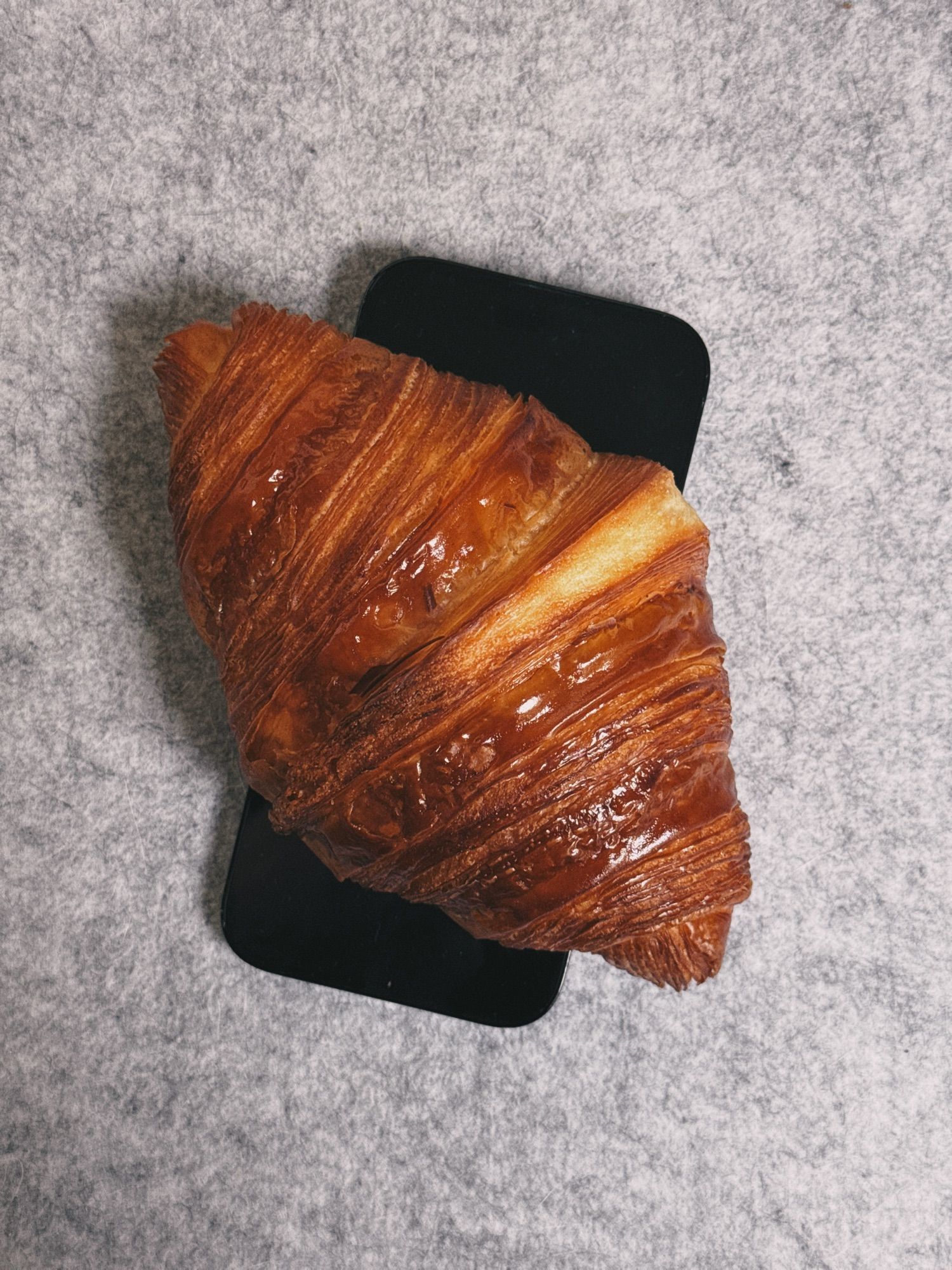 A croissant sitting on an iPhone