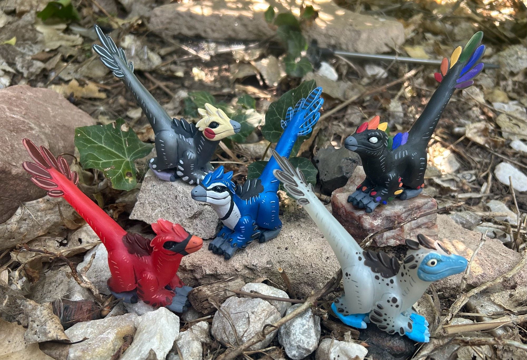 Five cute raptor figures posed on rocks.