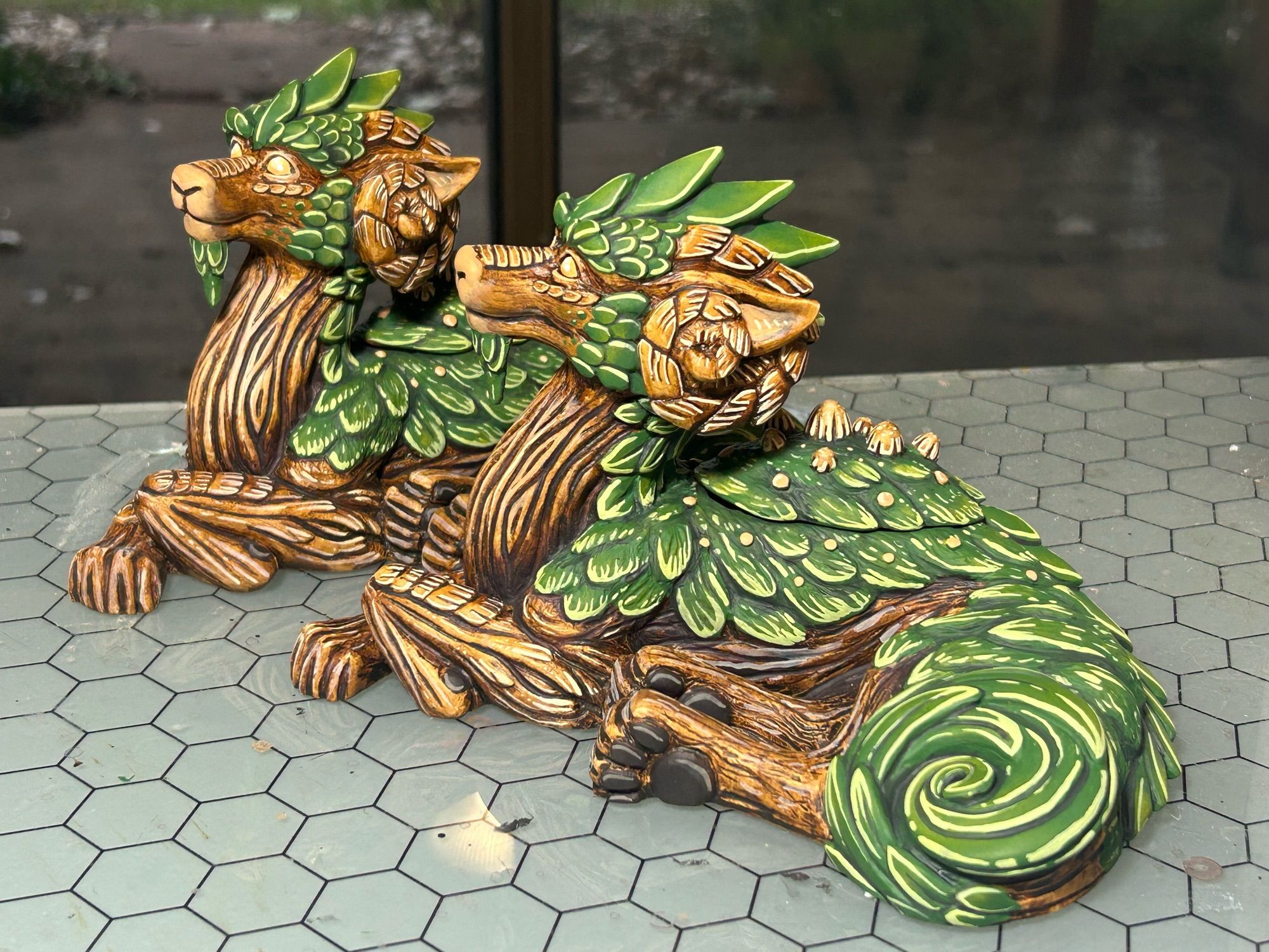 A pair of mossy tree themed dragon sculptures lying down.