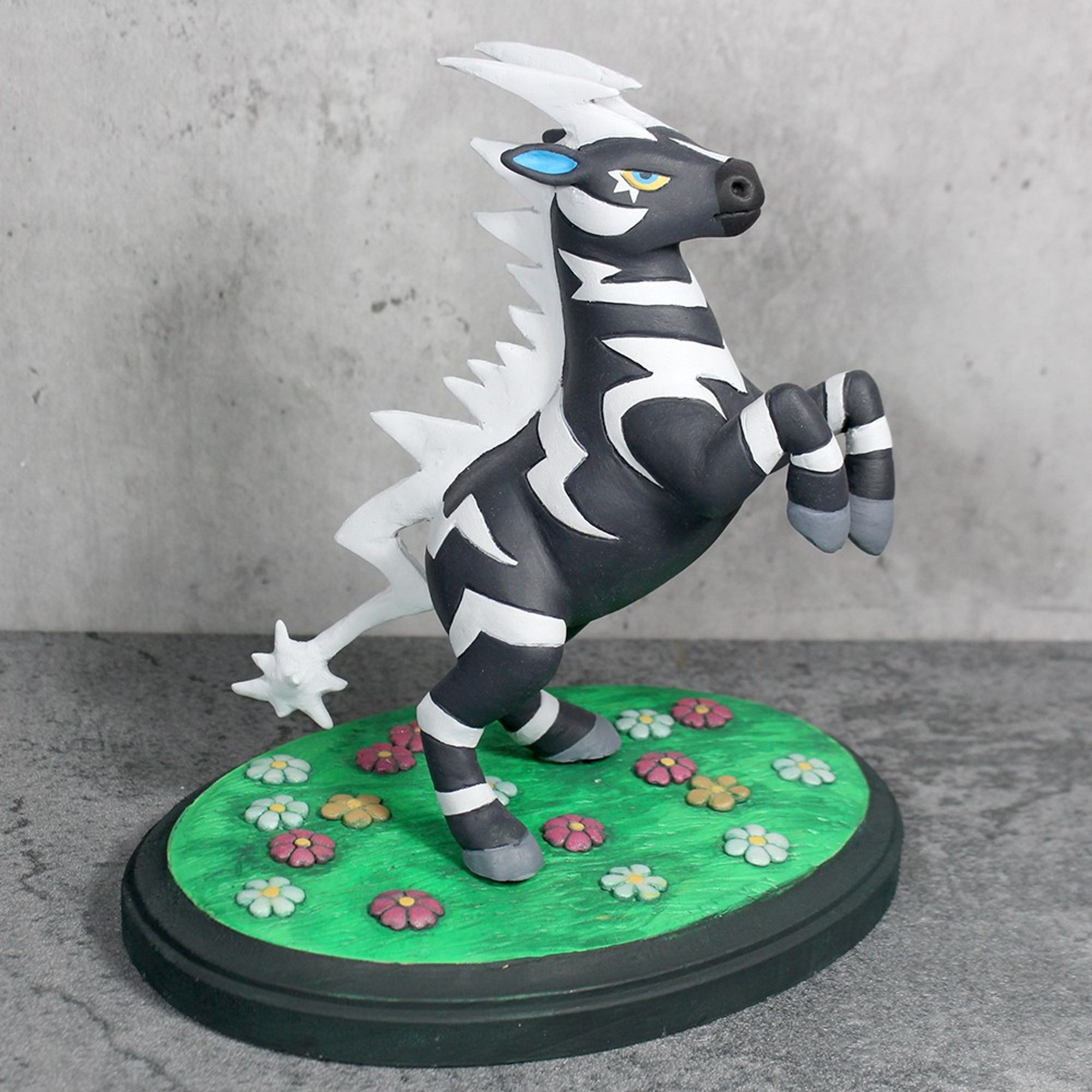 A sculpture of the Pokemon Zebstrika.  It is rearing on it's hind legs and stands atop a patch of grass with pastel flowers.