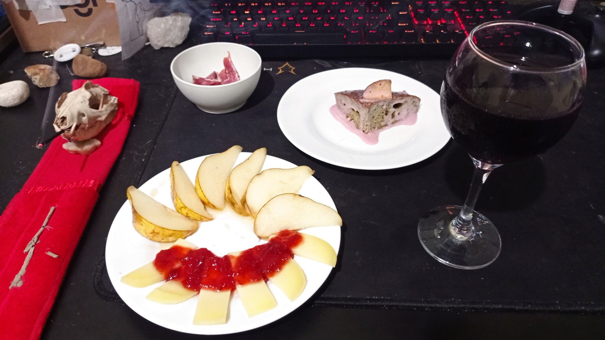 A glass of wine, a slice of hibiscus cake, a plate full of pears with honey and colonial cheese with homemade strawberry jam, and a bowl with pieces of cured meat. Delicious. Oh also a possum skull is smoking an incense in the corner, over a red cloth with the chin rested on a piece of quartz.