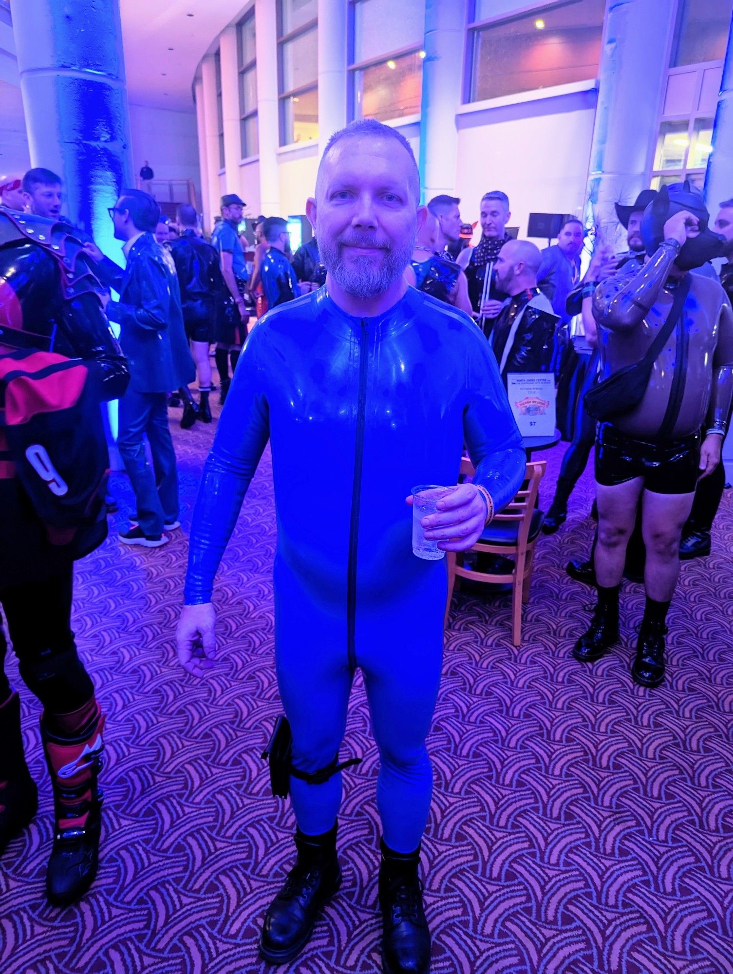 Me standing in a lobby in a royal blue rubber catsuit