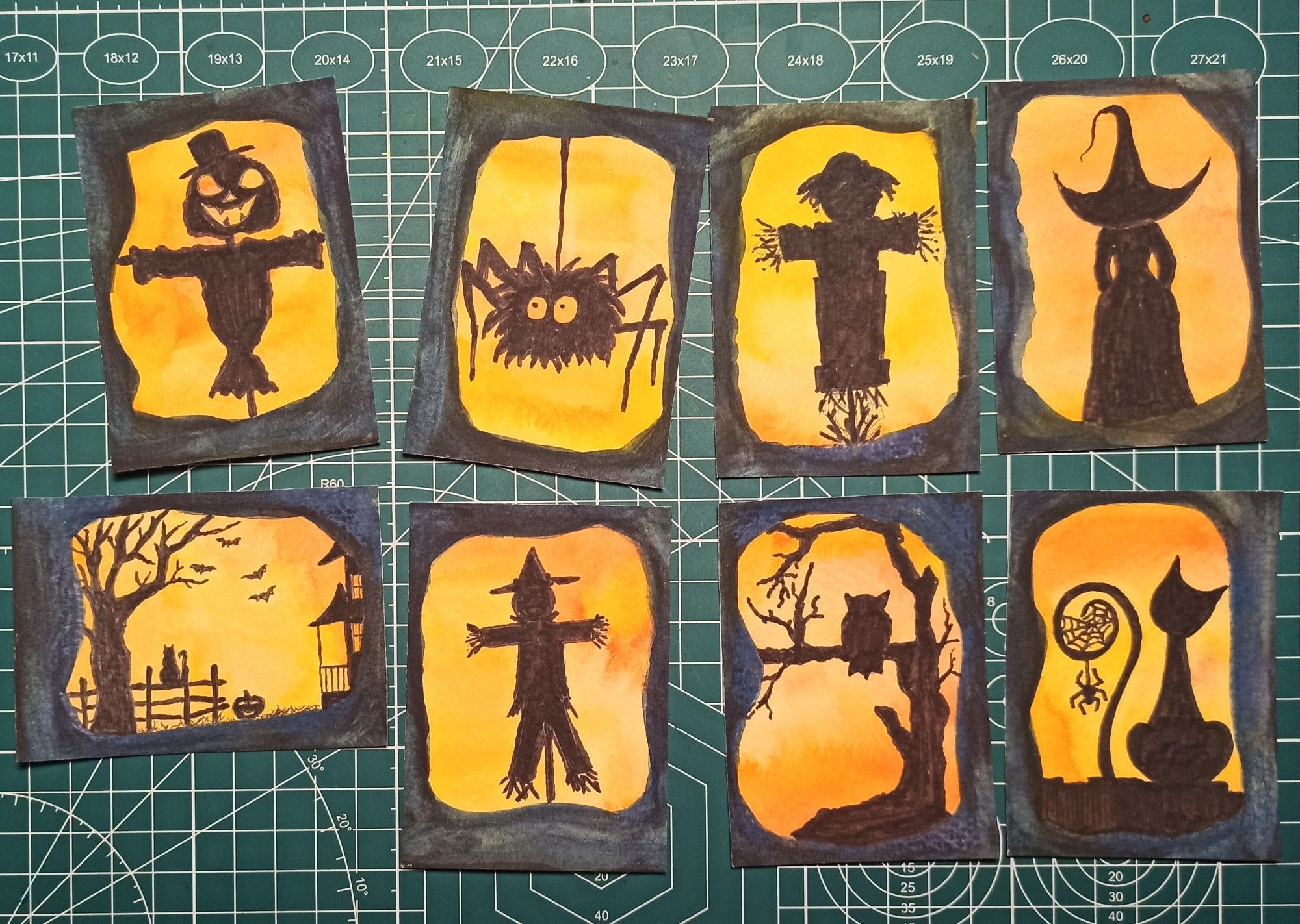 Acht ATC mit schwarzen Silhouetten von Halloween. 
Oben: Vogelscheuche, Spinne, Vogelscheuche, Hexe von hinten. 
Unten: kleine Landschaft mit Baum, Haus, Zaun, Katze und einem Kürbis; am Himmel vier Fledermäuse, 
Vogelscheuche, Eule auf Baum, Katze