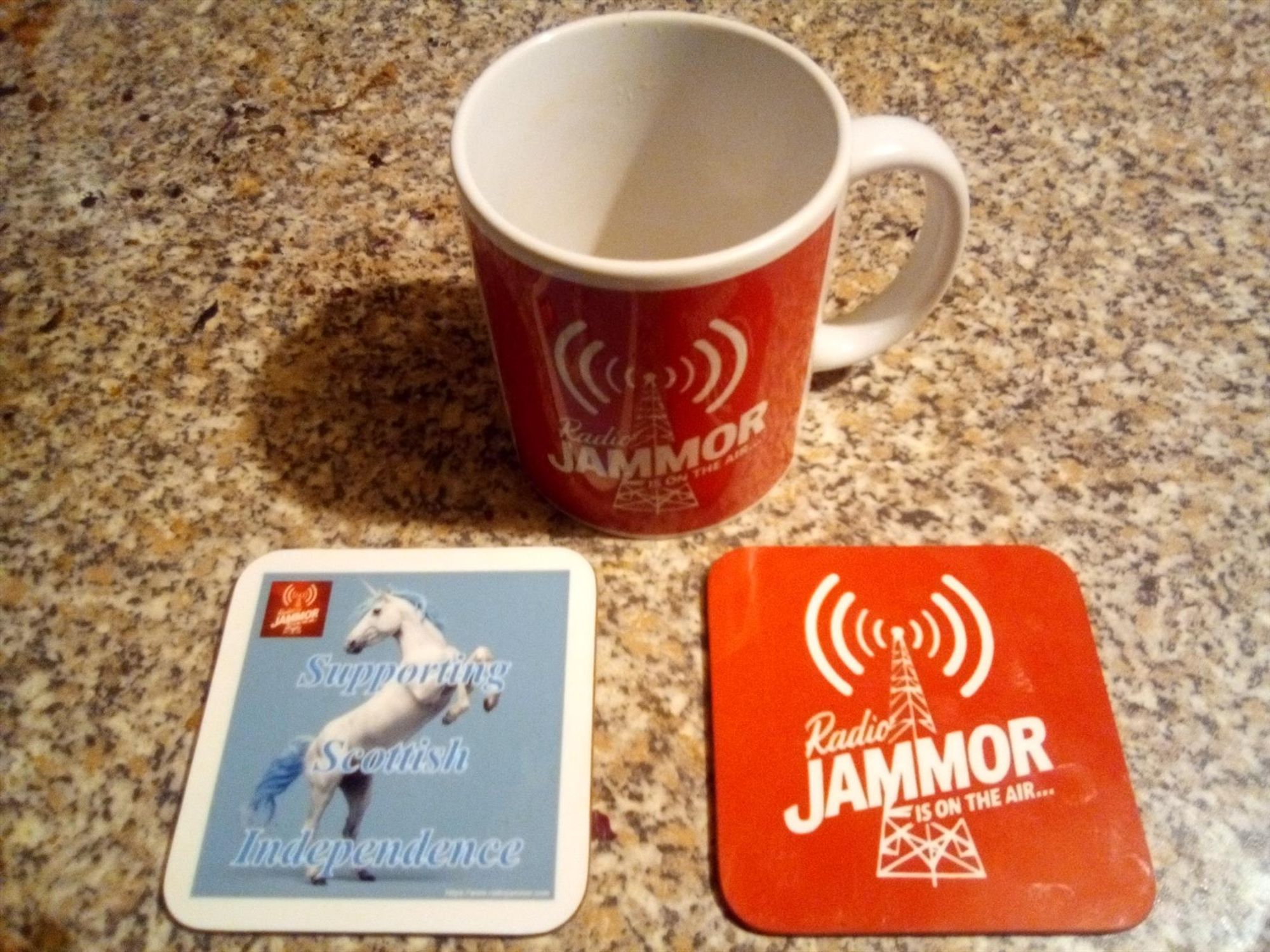 Radio Jammor mug (with new 2024 logo), two coasters, one with the new logo, one with the Radio Jammor Unicorn, "Supporting Scottish Independence" text, with new logo top left.