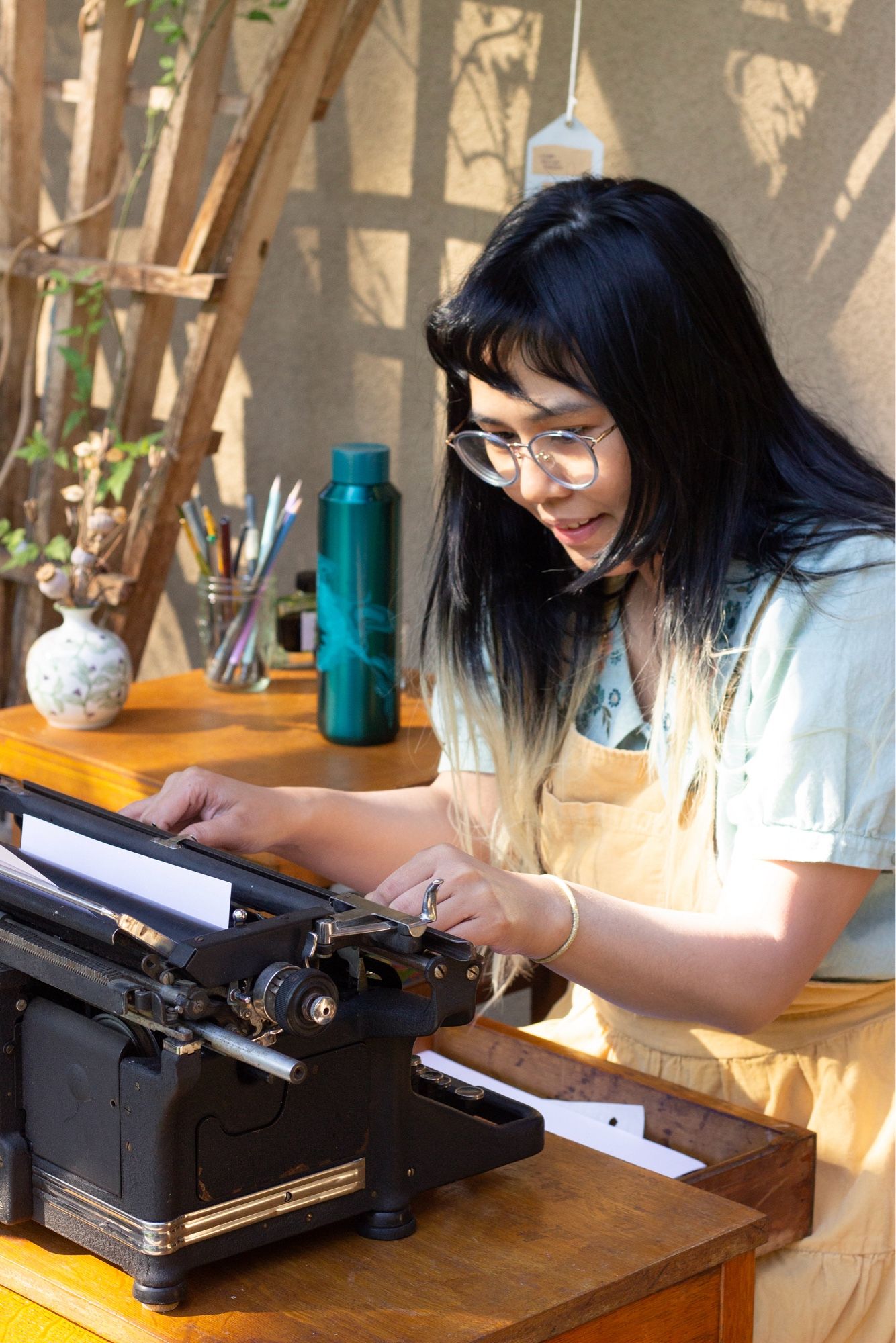 An artist sits down at a wooden desk to experiment with an old typewriter