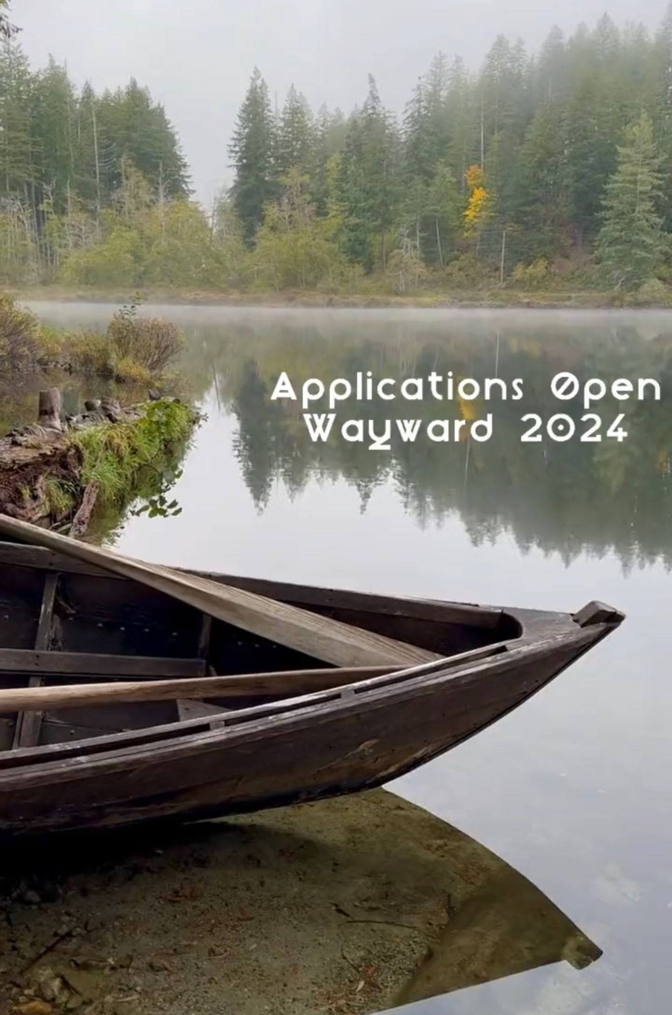 The front of a wooden rowboat rests on the edge of a lake, with mist a d pine trees in the distance. Text reads: applications open Wayward 2024"