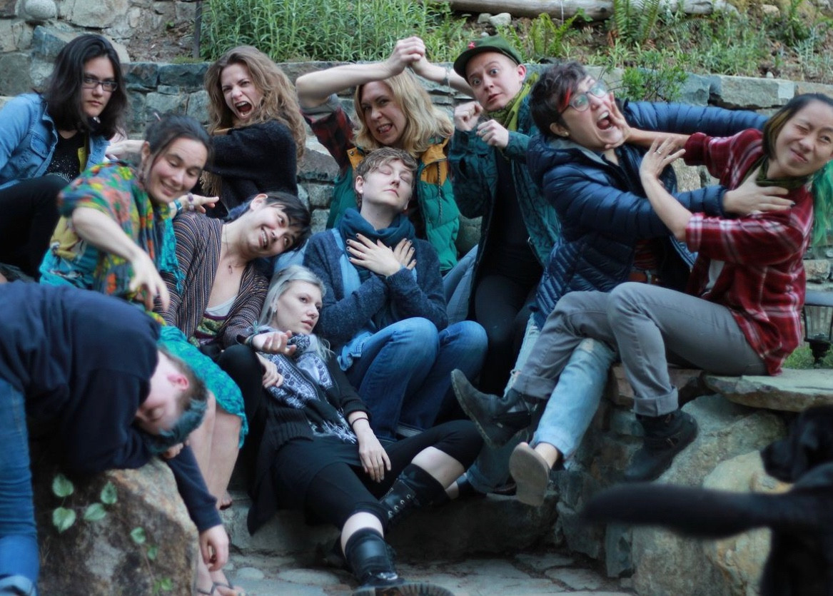 A group photo of retreaters on stone steps, posing to a prompt along the lines of “murder house!”