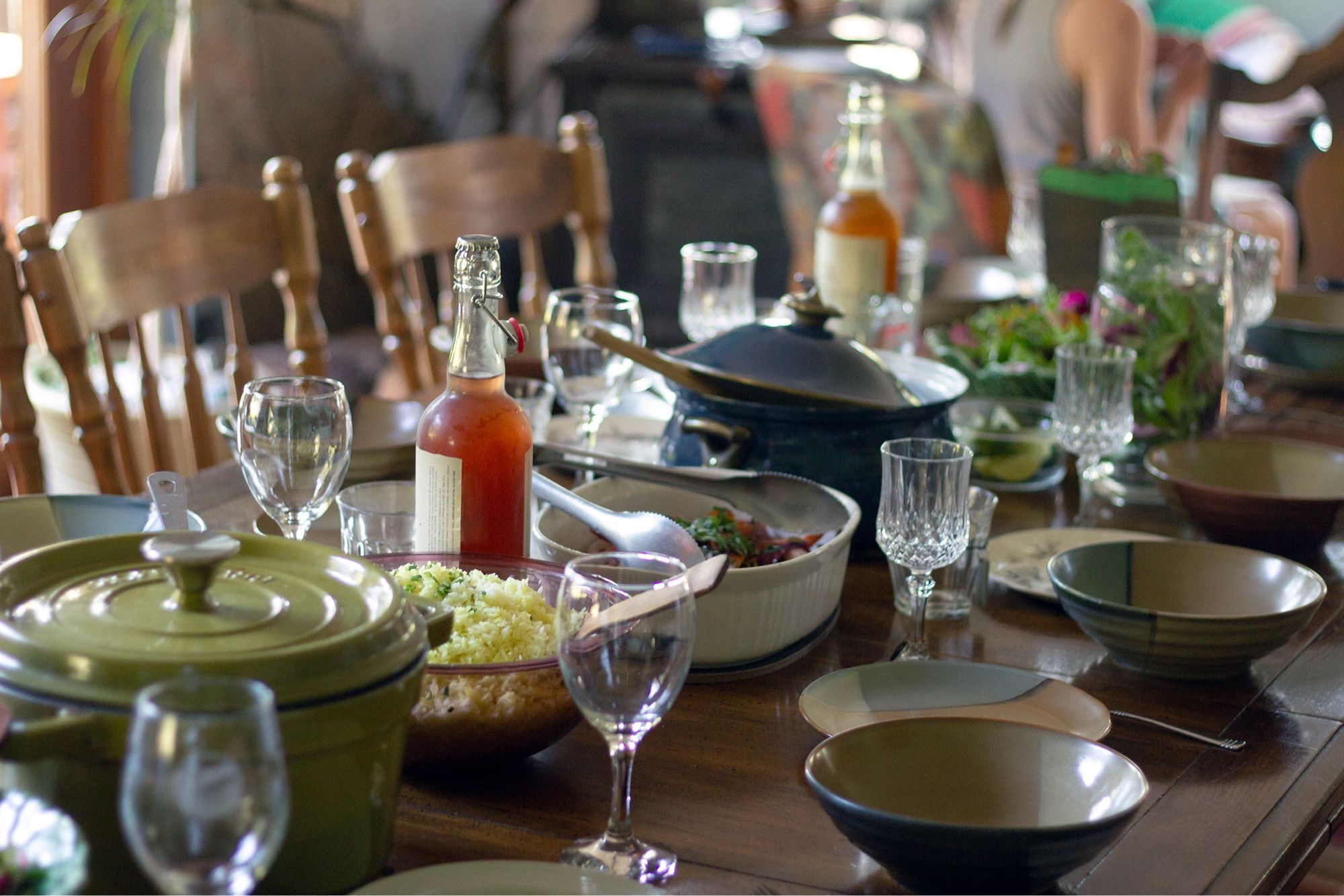 A dinner table piled with a lovely dinner and bottles of cider, waiting for a group to sit down and eat