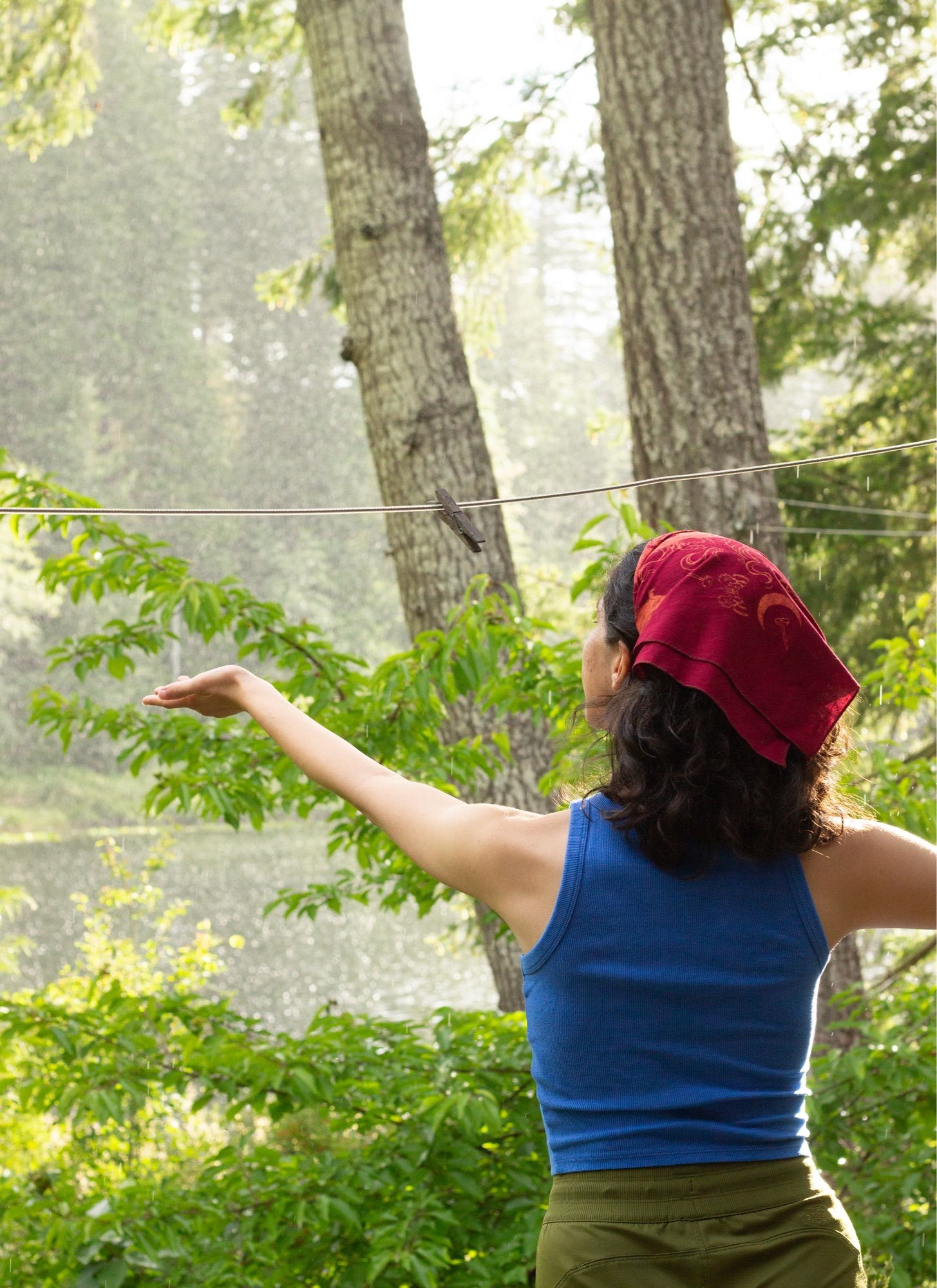 An artist stretches their hand out from a covered porch to catch some rain