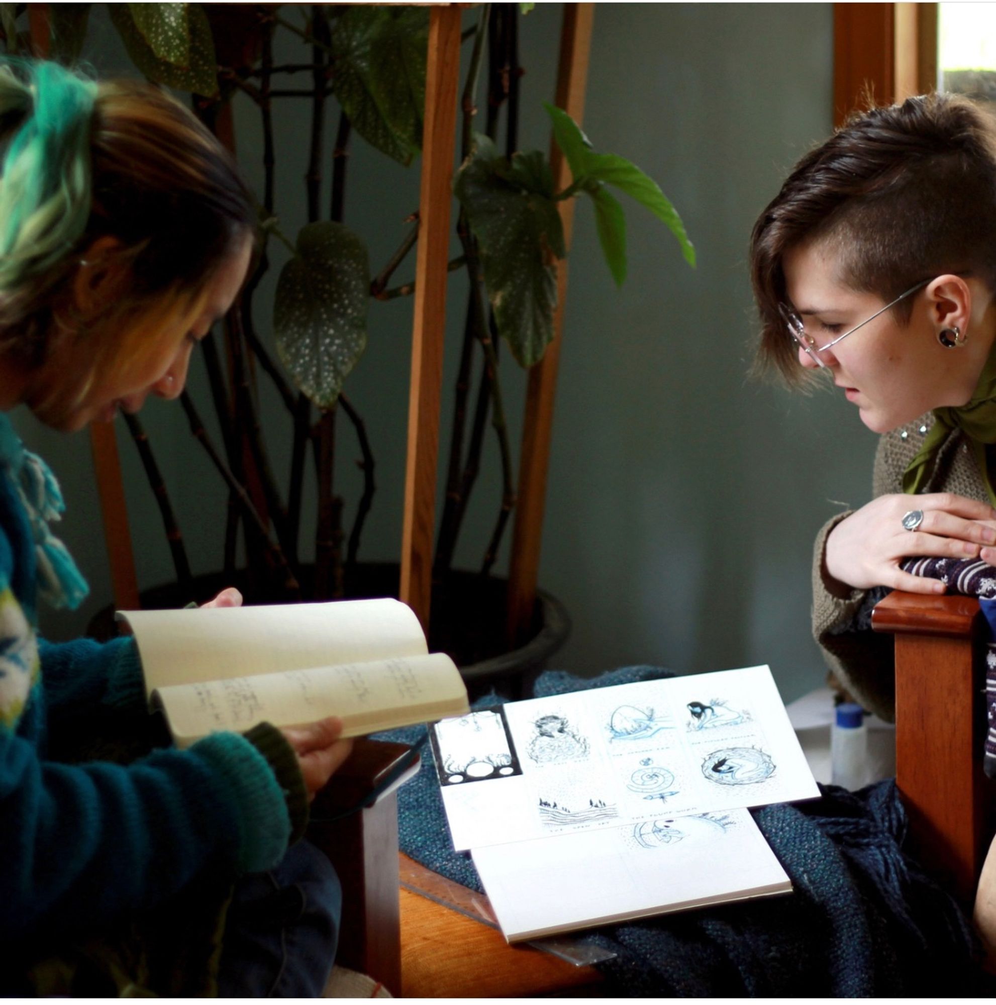 Two retreaters lean together to discuss notebooks of illustration and writing