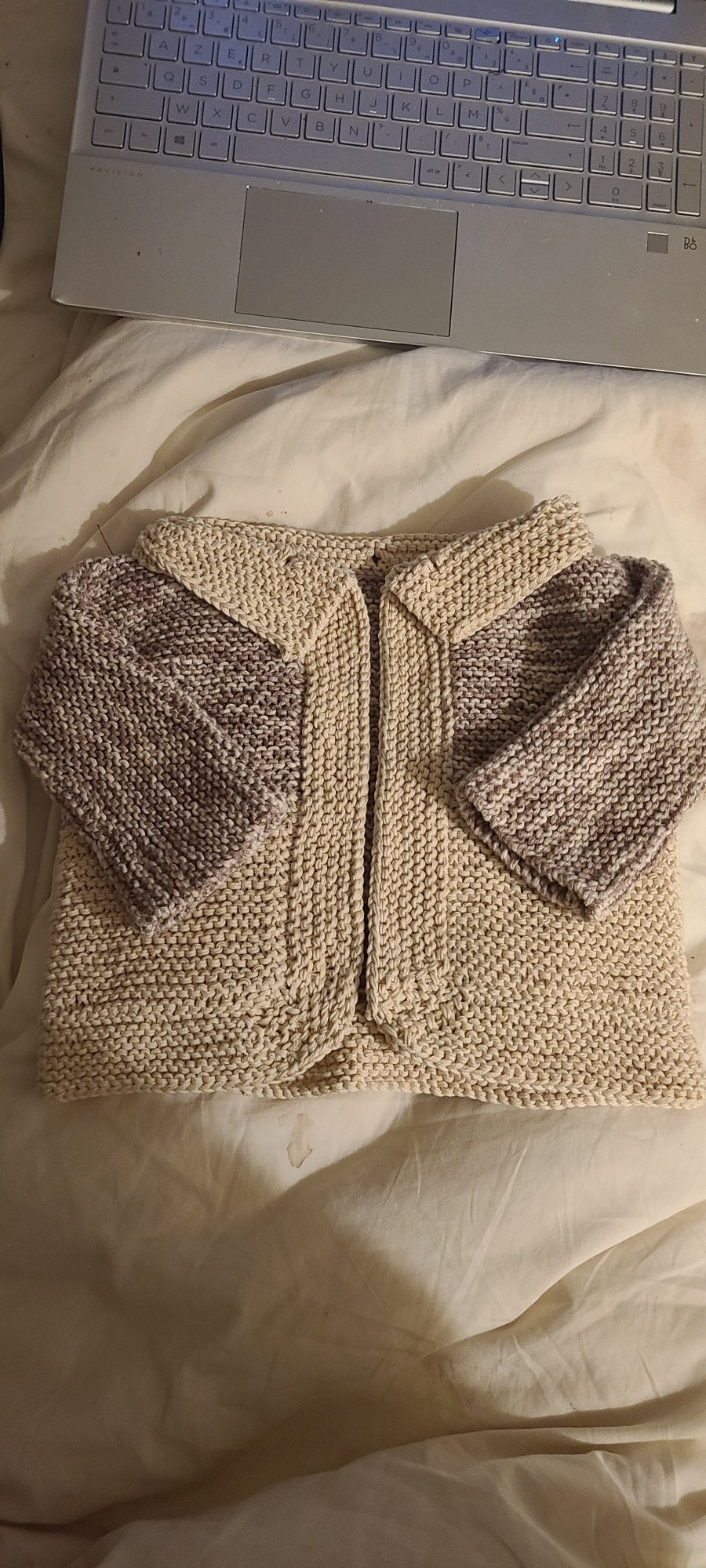 A little knit cardigan muted brown and creme on white sheets