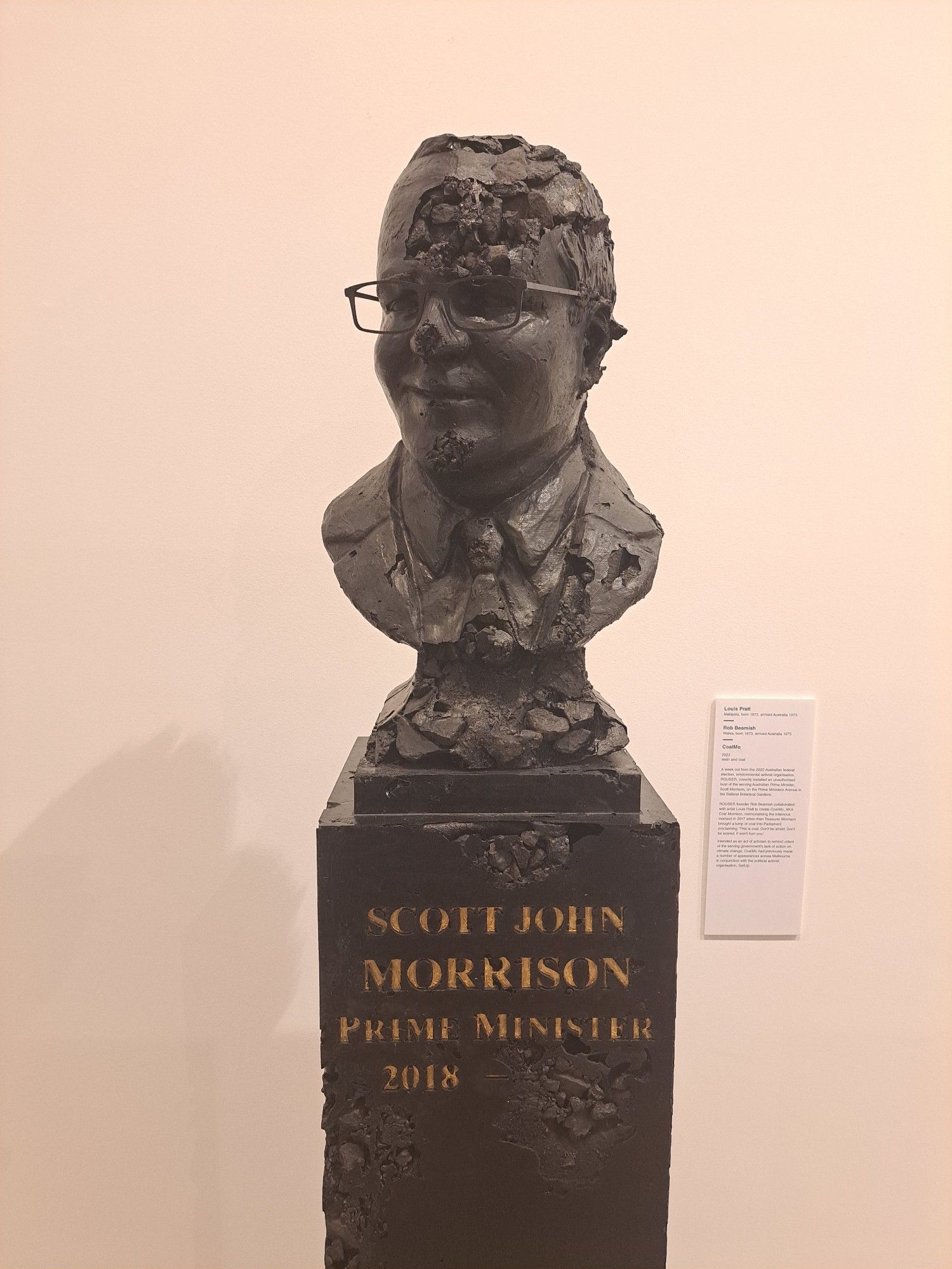 A busy of former PM Scott Morrison carved out of coal.  The forehead and bottom half of the bust are flaking away.  The inscription in gold in the base of the stature reads "Scott Morrison, Prime Minister,  2018-"