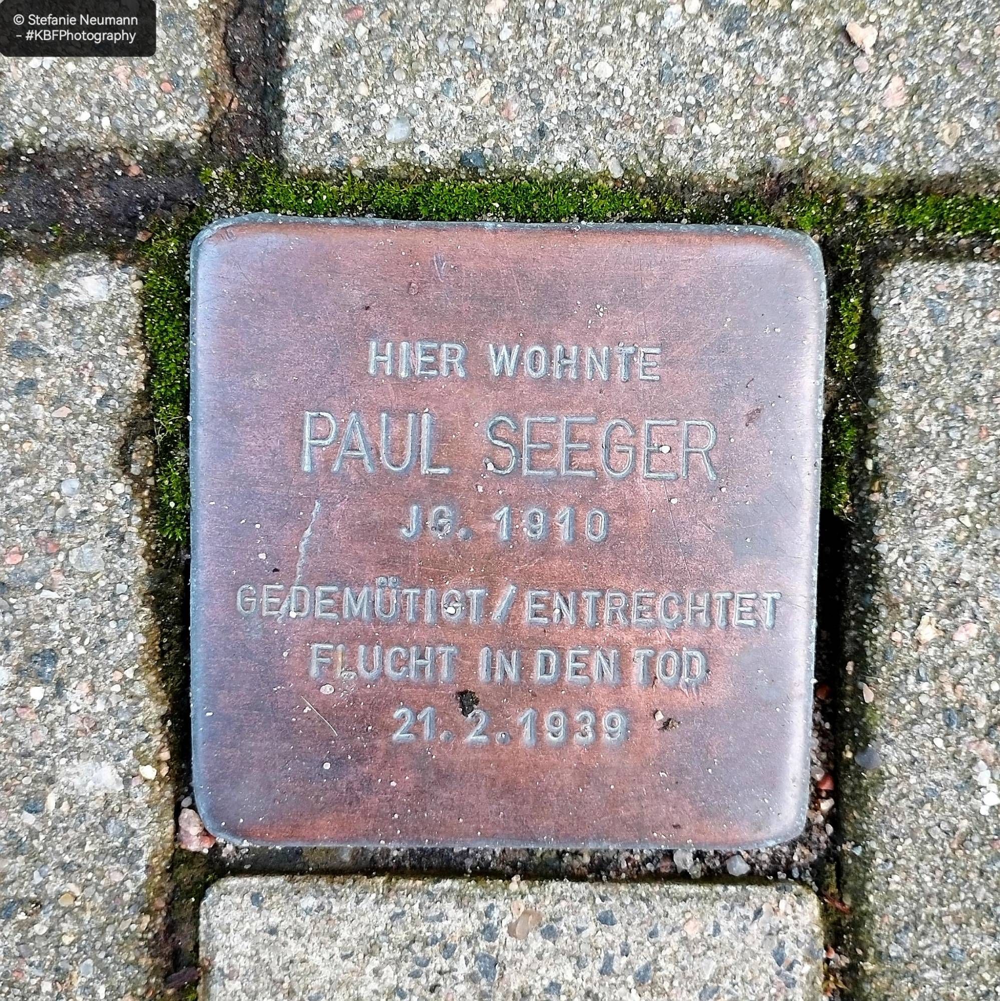 Ein Stolperstein. Er besagt:
Hier wohnte Paul Seeger, JG 1910
Gedemütigt/ Entrechtet, Flucht in den Tod 21.2.1939