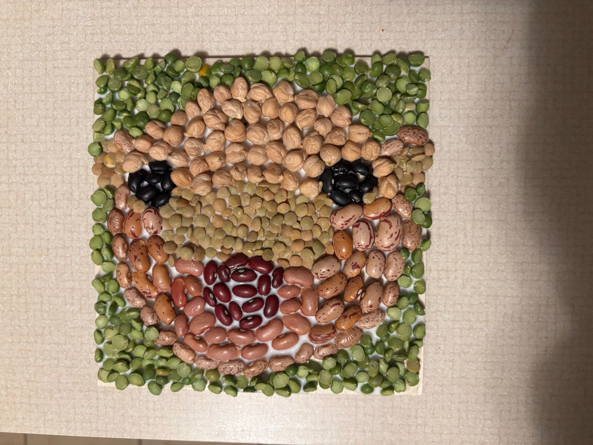 A mosaic of beans that looks vaguely like Moo Deng