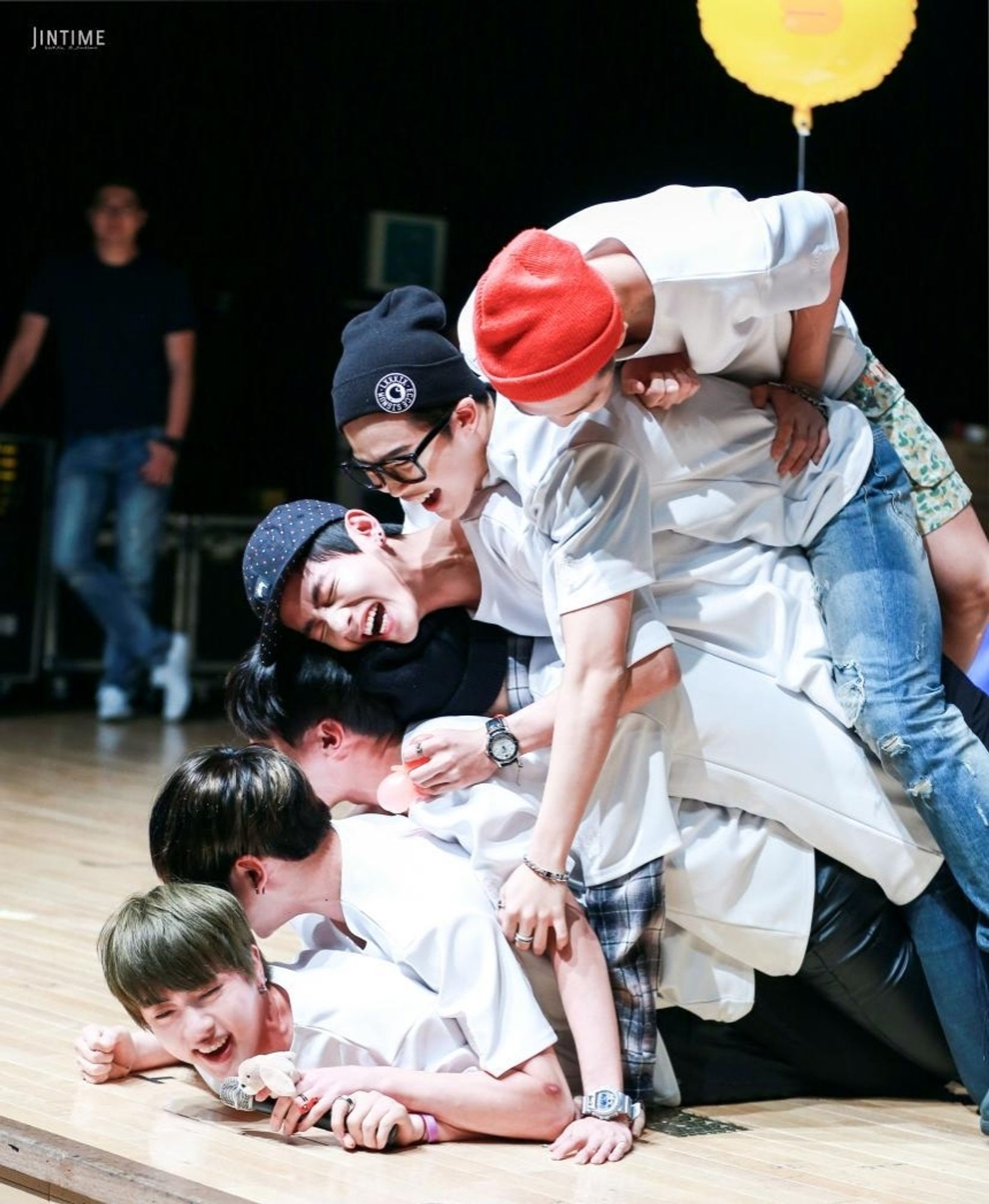 BTS members lying on each other like a puppy pile, laughing hysterically