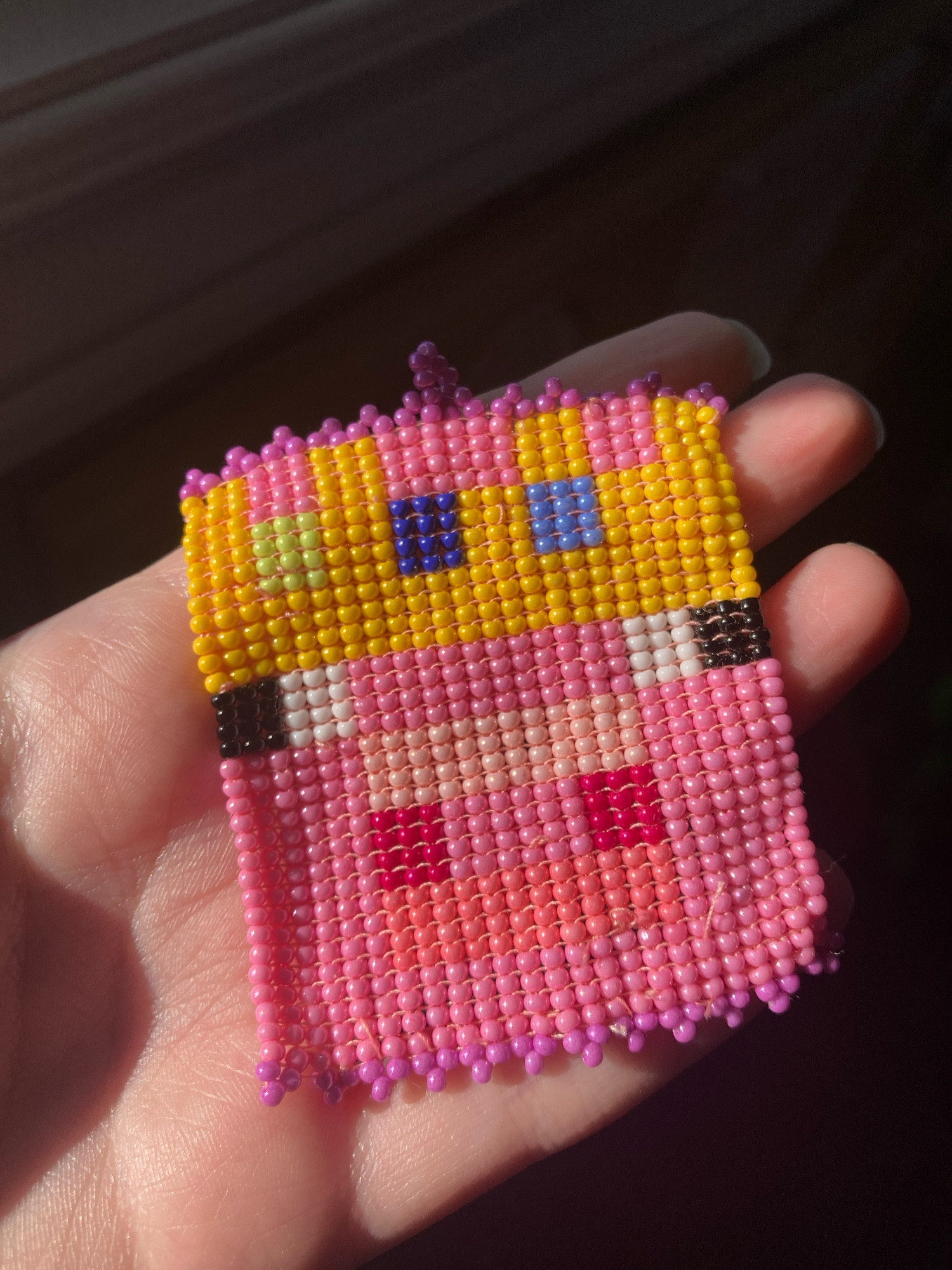 Small seed beads square stitched in the likeness of Minecraft YouTuber Technoblade with purple beads on the top and bottom edges