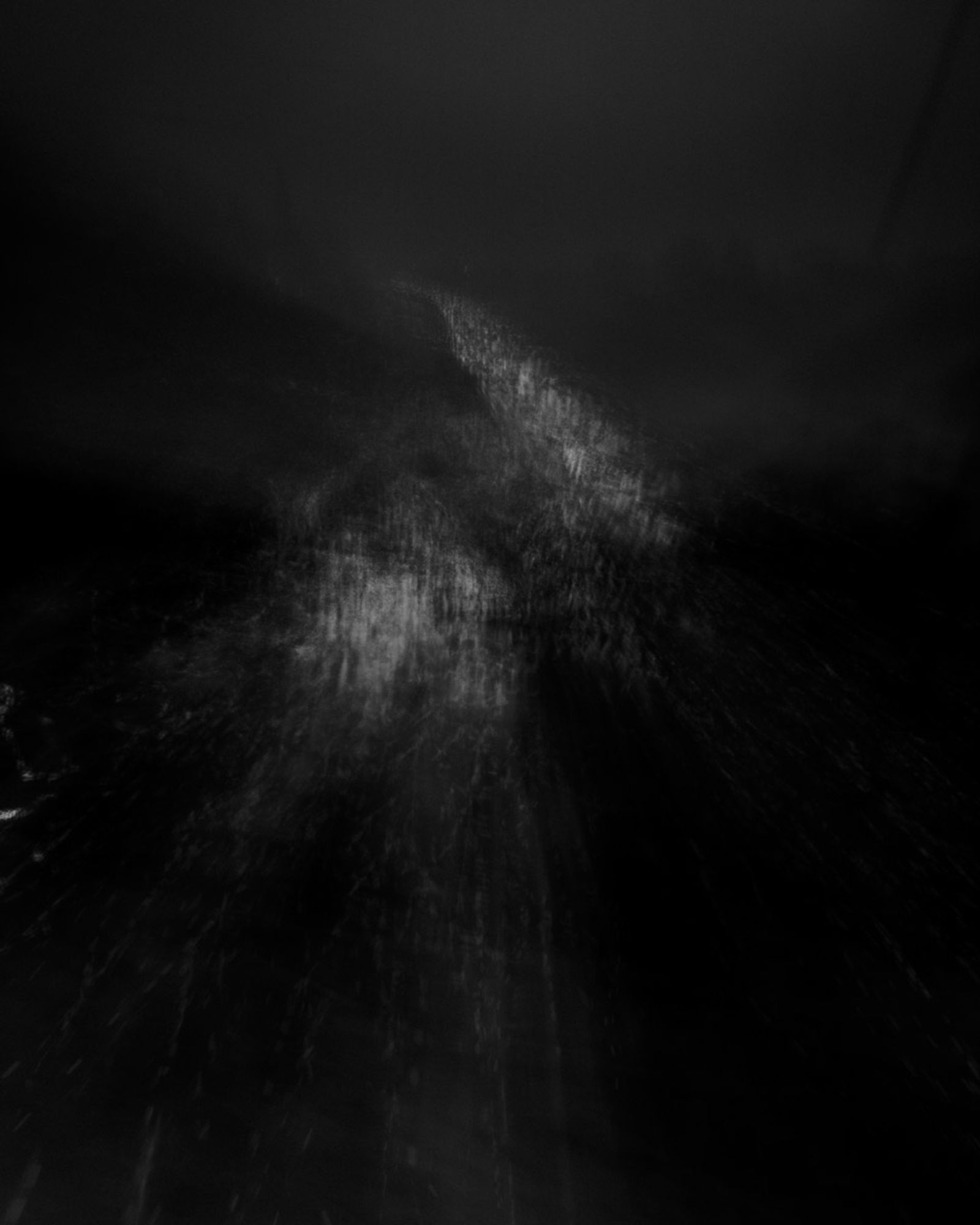 Abstract and very dark, mysterious photograph, a suggestion of dark forested hills with vaporous lights moving between