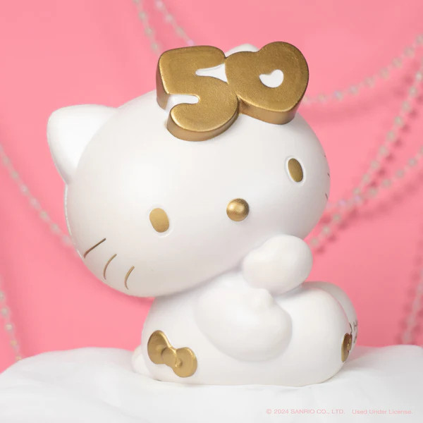 a white hello kitty squishable stress toy, with gold accents and 50 where the bow should be