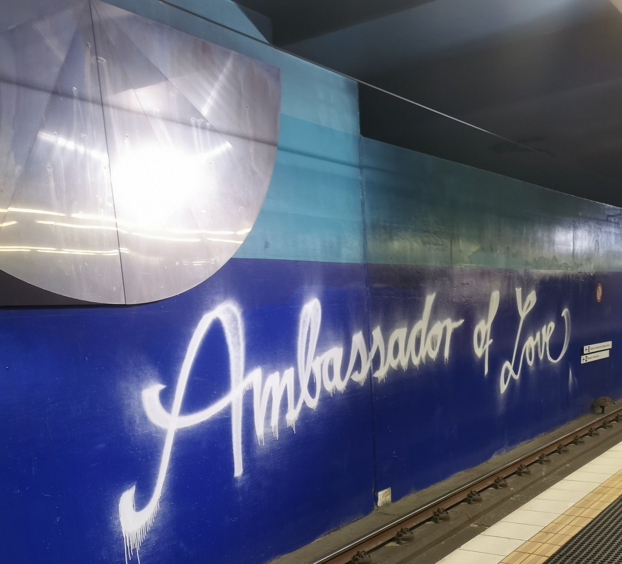 Metro Station in Cologne. Spraying white on blue saying: "Ambassador of Love"