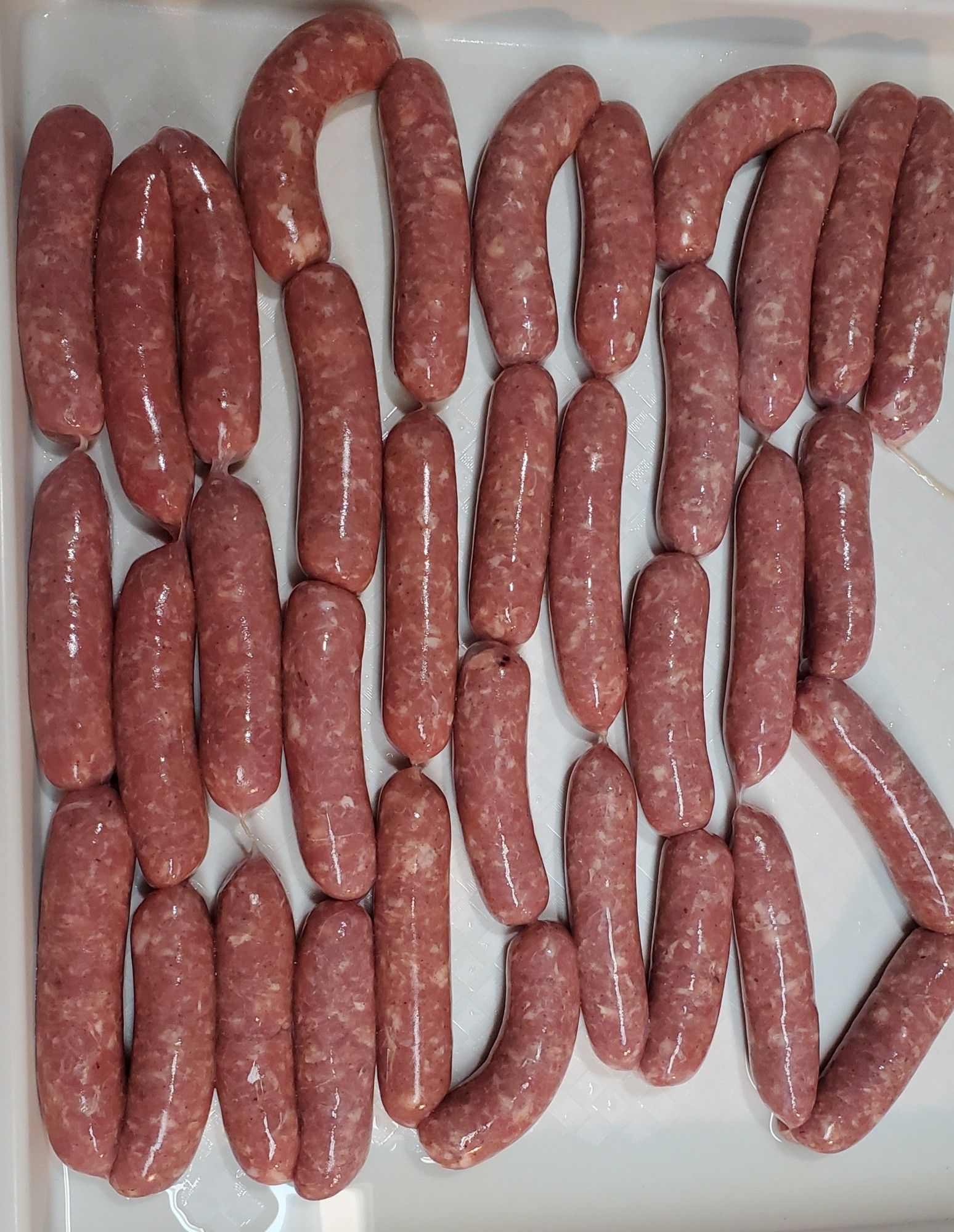 A string of homemade breakfast sausage links on a white tray.