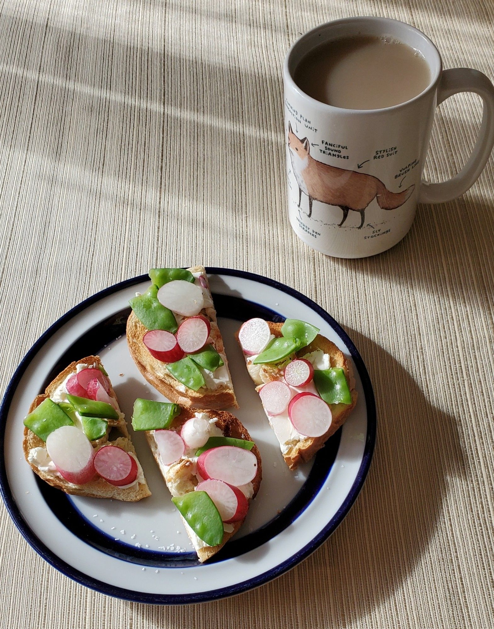 A bagel cut into quarters, topped with green snow peas and red and white radishes. And a mug of milky tea.