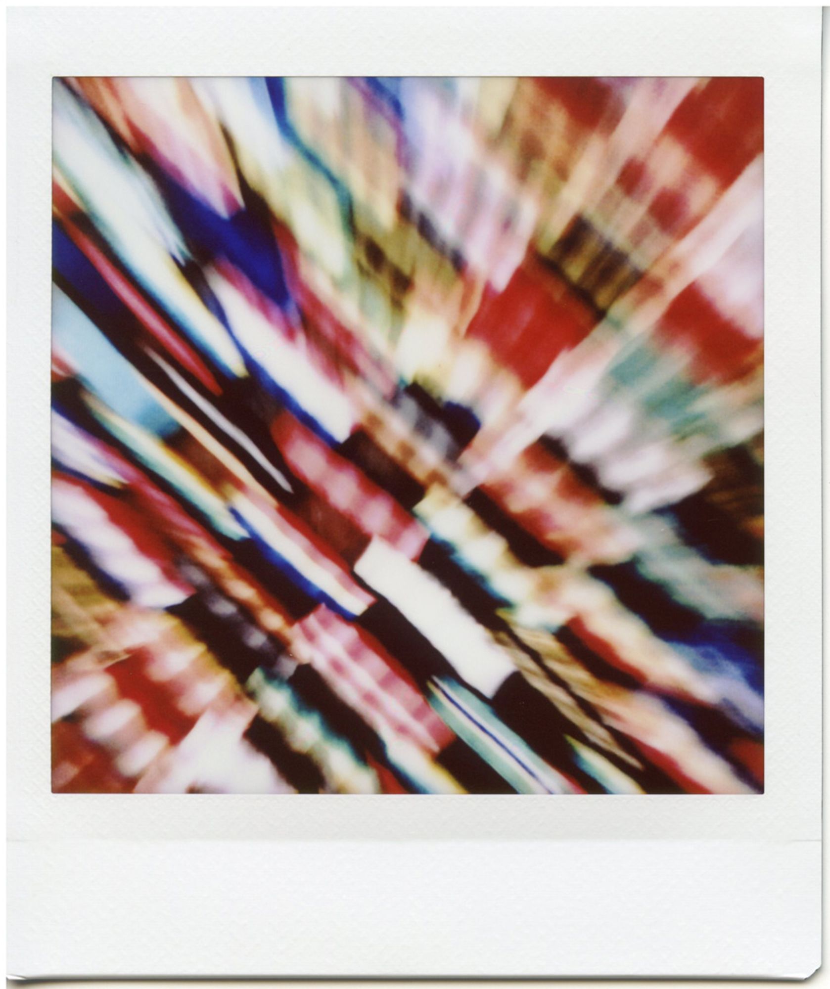 A color instant photograph of a multi-colored rubber doormat with a zoomed out blur.