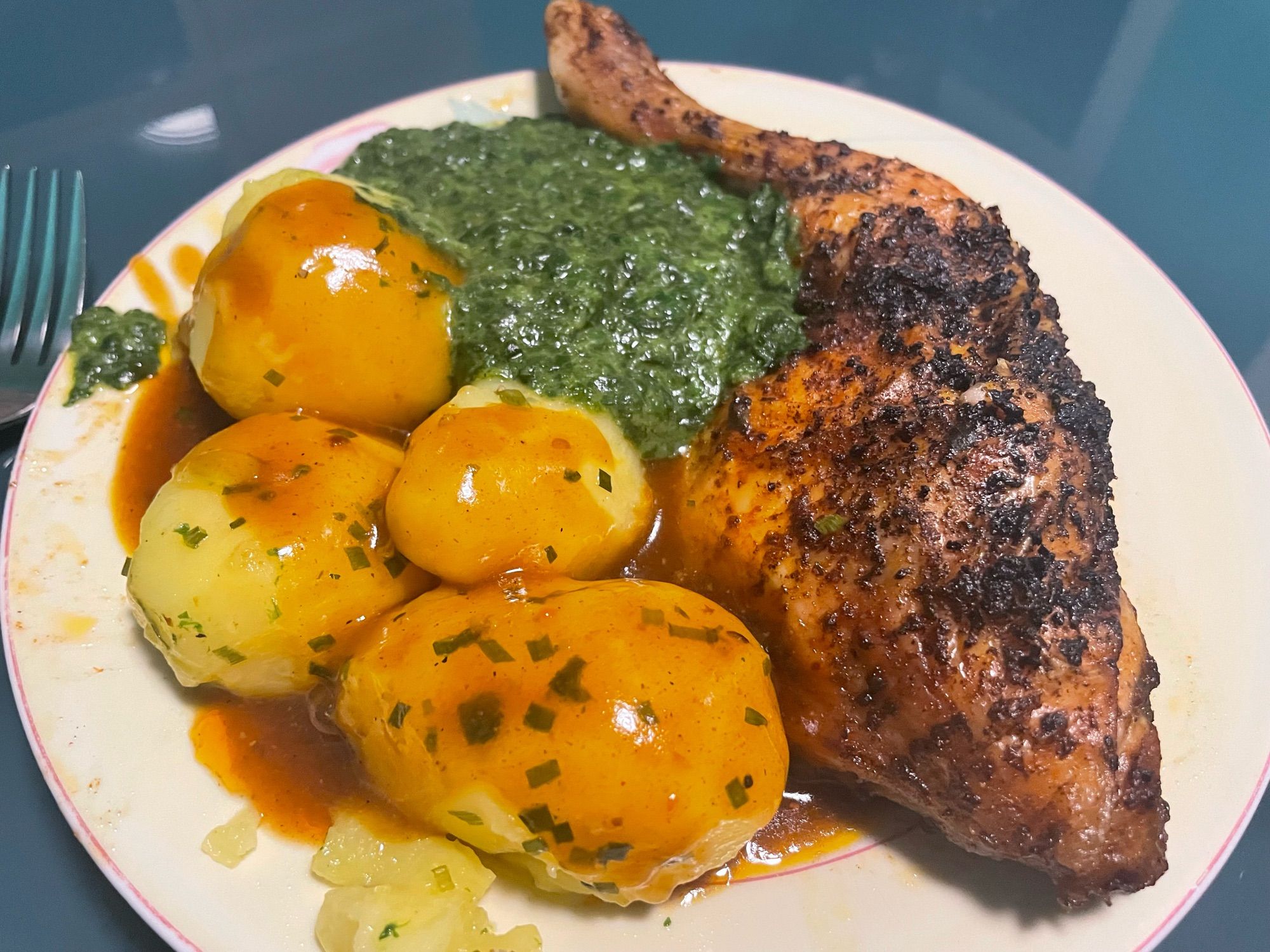 Oven roasted chicken thighs, creamy spinach and buttered chive potatoes with gravy from the chicken thigh’s roux on a large plate.