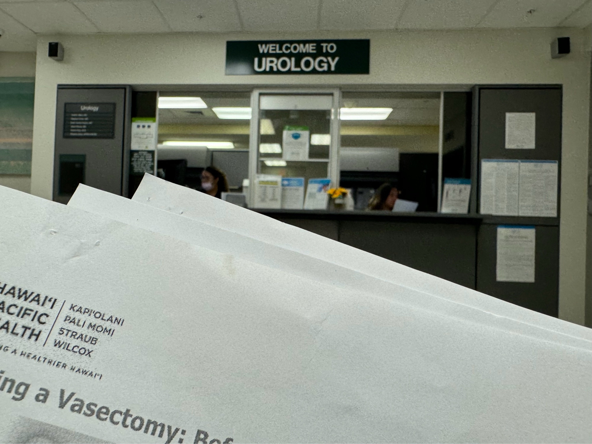 Hospital waiting room, "Welcome to Urology" sign on the wall, paper form in foreground, "Having a Vasectomy."