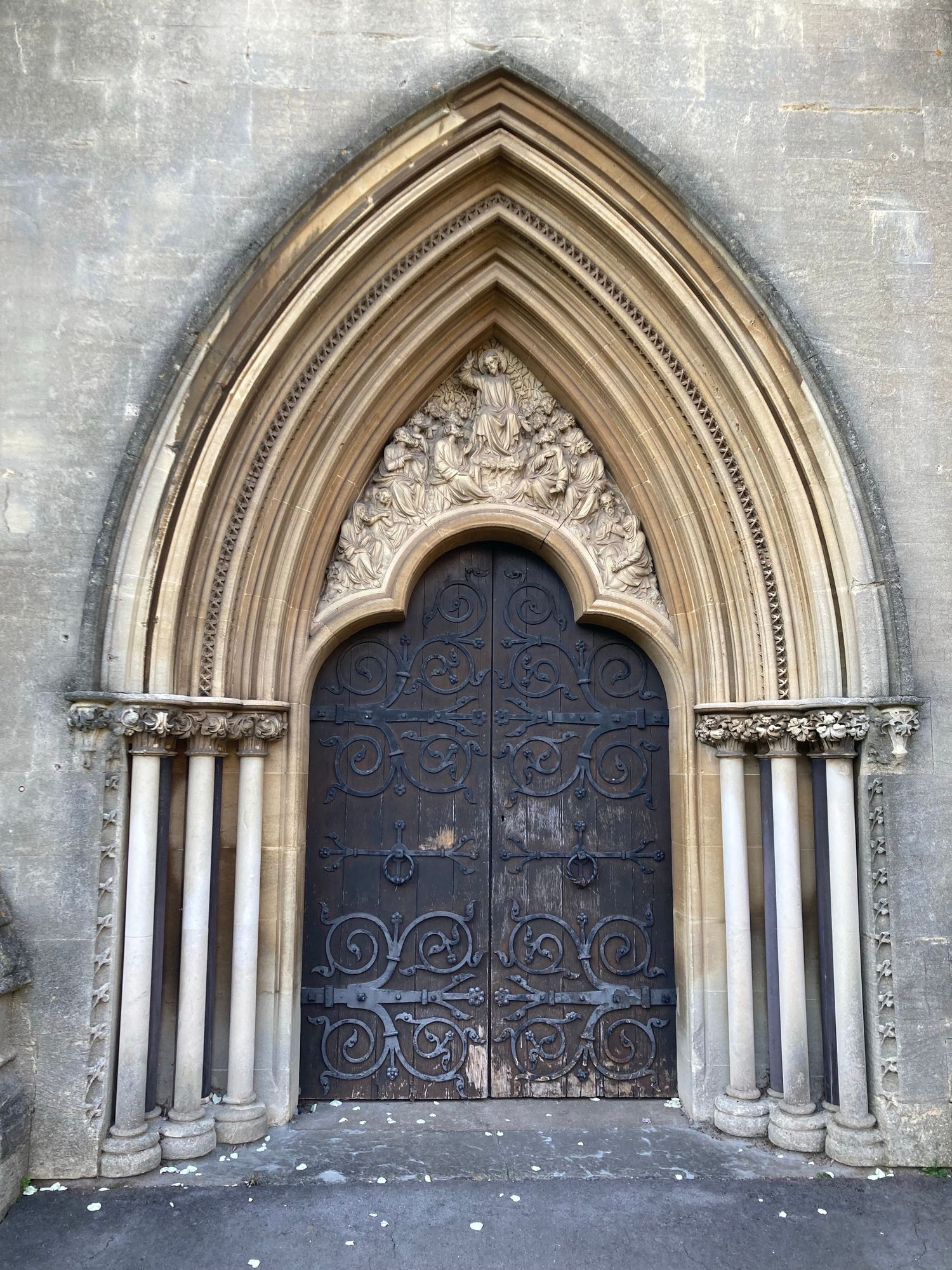 Stone carving above wooden exterior door. Showing the christ above disciples either side