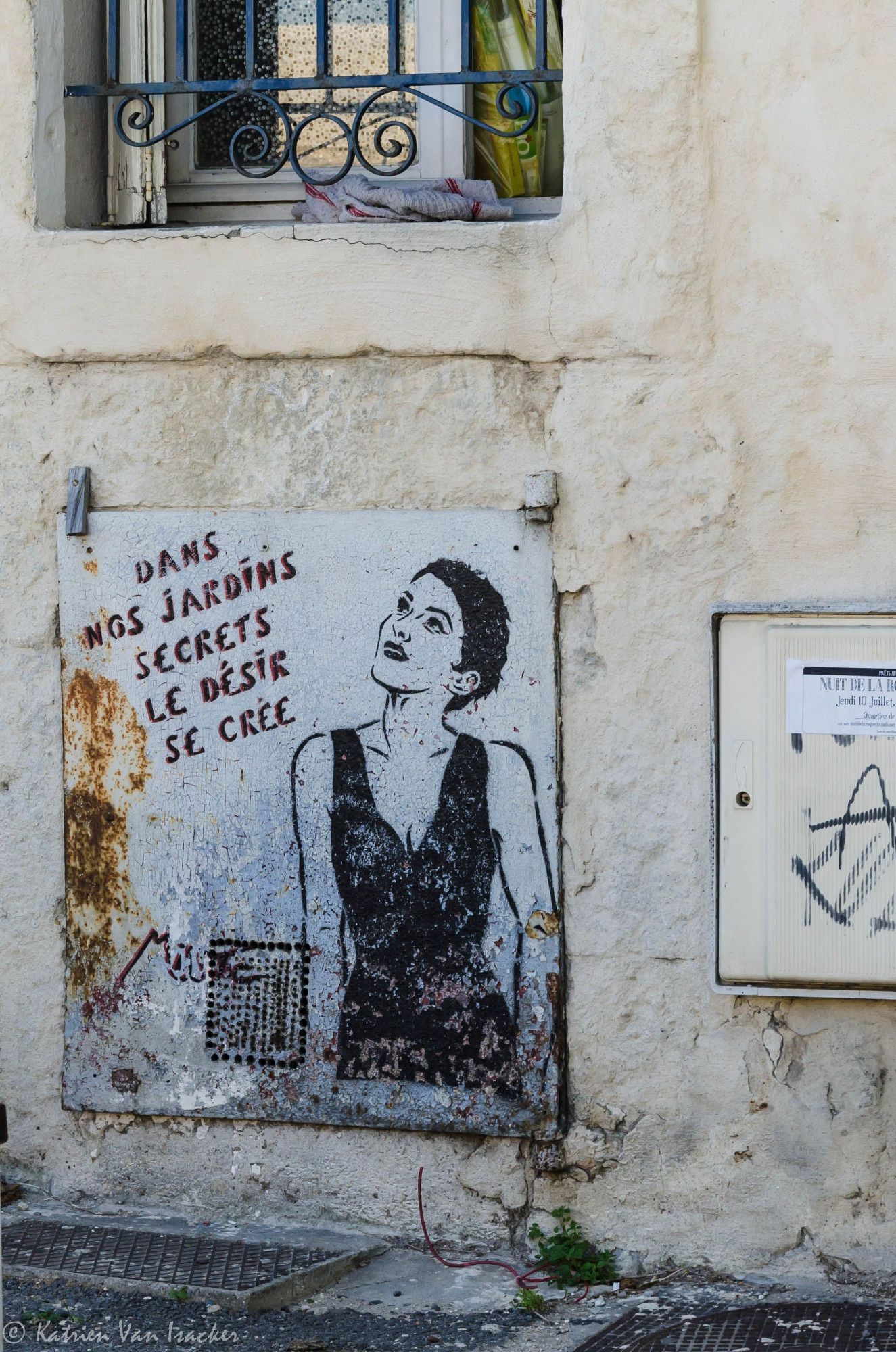 La photo montre une œuvre de street art de Miss.Tic sur un mur. L’art présente une image pochoir d’une femme brune portant une robe.
Sur le côté, il y a un aphorisme : “Dans nos jardins secrets le désir se crée”.