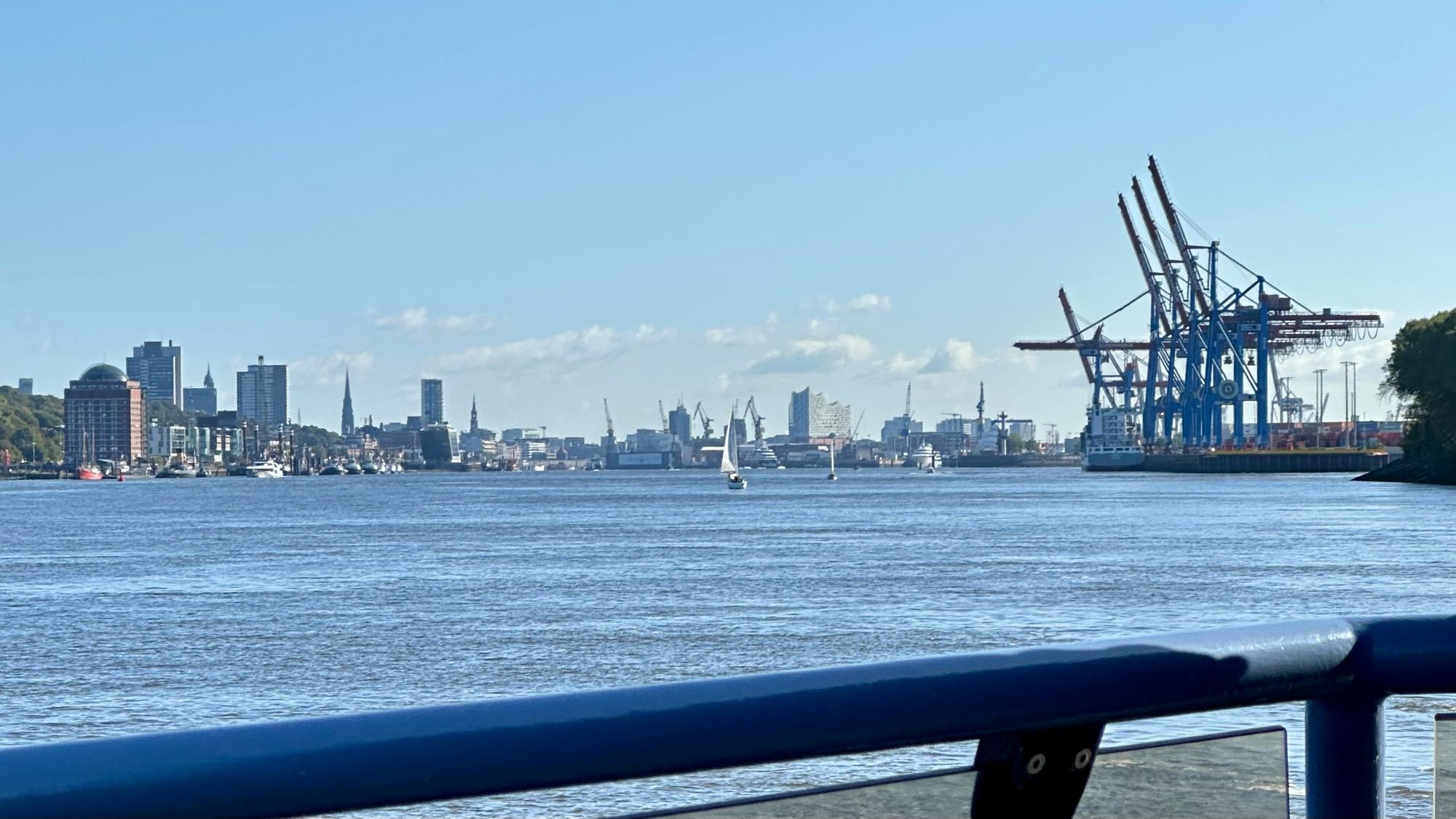 Blick von einer Elbfähre Richtung Landungsbrücken. Rechts Hafenkräne, mittig und links Skyline der Stadt/ Hafen