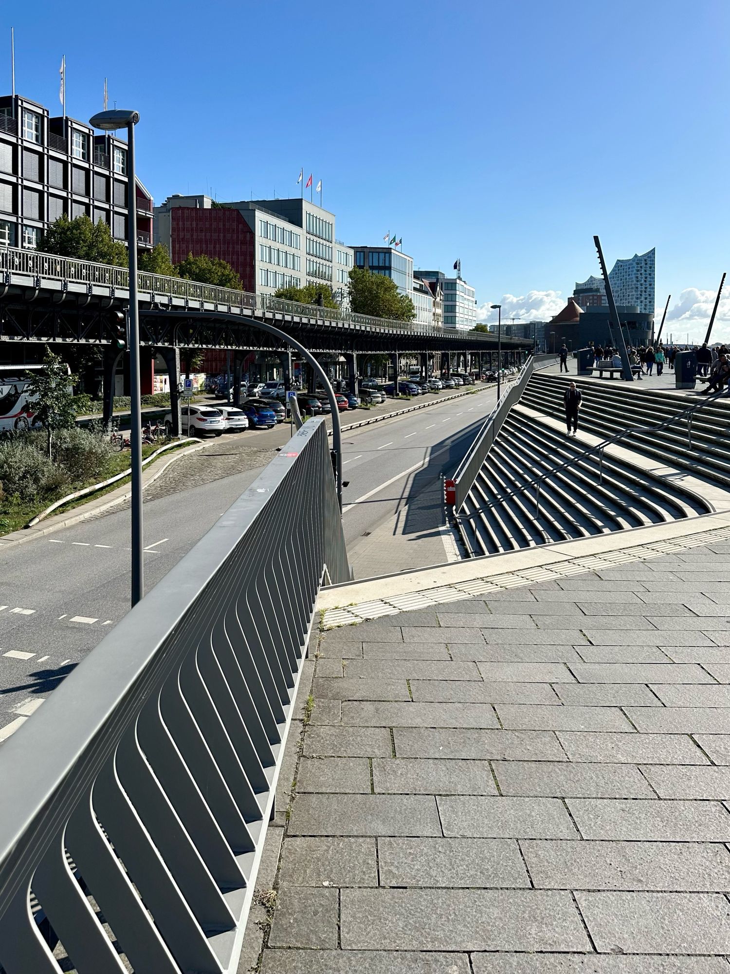 Treppen mit Geländer nahe den Hamburger Landungsbrücken links Hochbahn und Häuser, rechts Treppen. Im Hintergrund Elbphilharmonie.