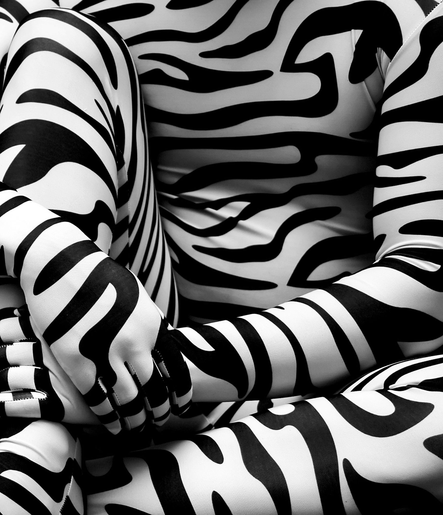 Black and white photo closeup of a figure in a zebra print zentai